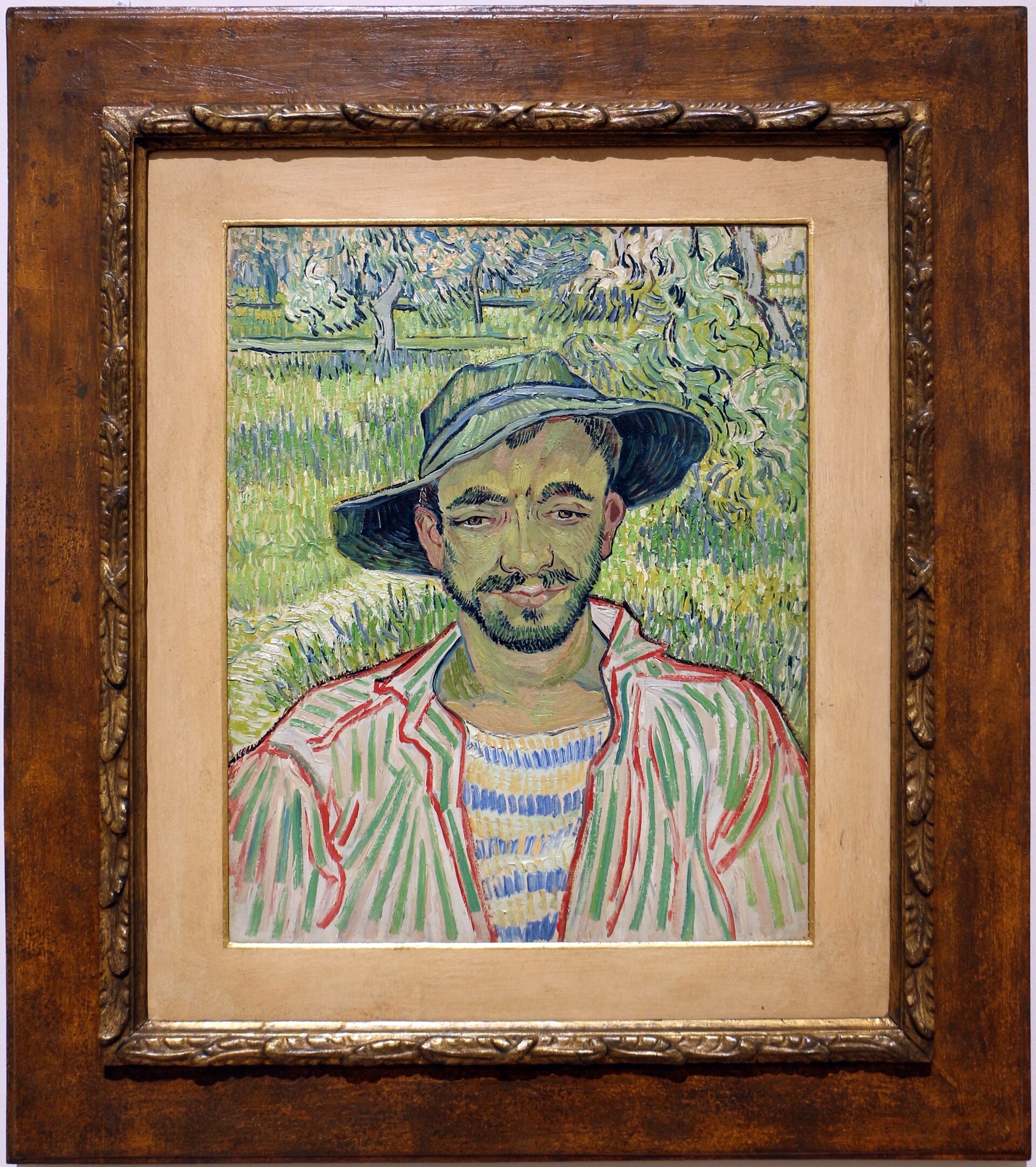il giardiniere di van gogh, un uomo con il cappello di paglia e la camicia a righe davanti a un frutteto verde in fiore