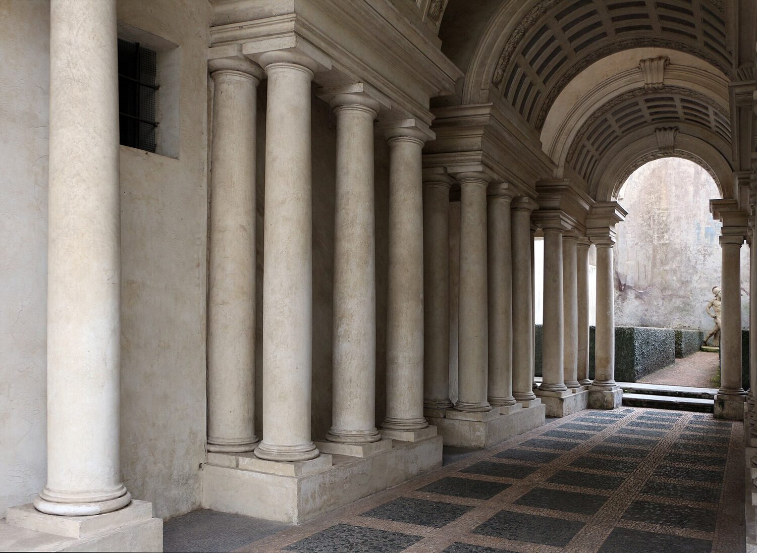 la volta cassettonata che si abbassa e le colonne che si accorciano verso il giardino