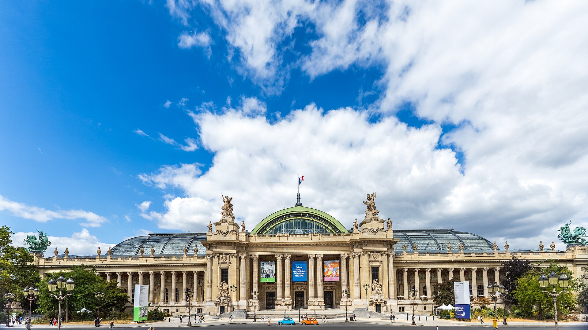 la facciata principale del grand palais vista dagli champs elysees con le due quadrighe dorate agli angoli del tetto, la cupola verde della nef e gli striscioni delle mostre in corso sopra il colonnato