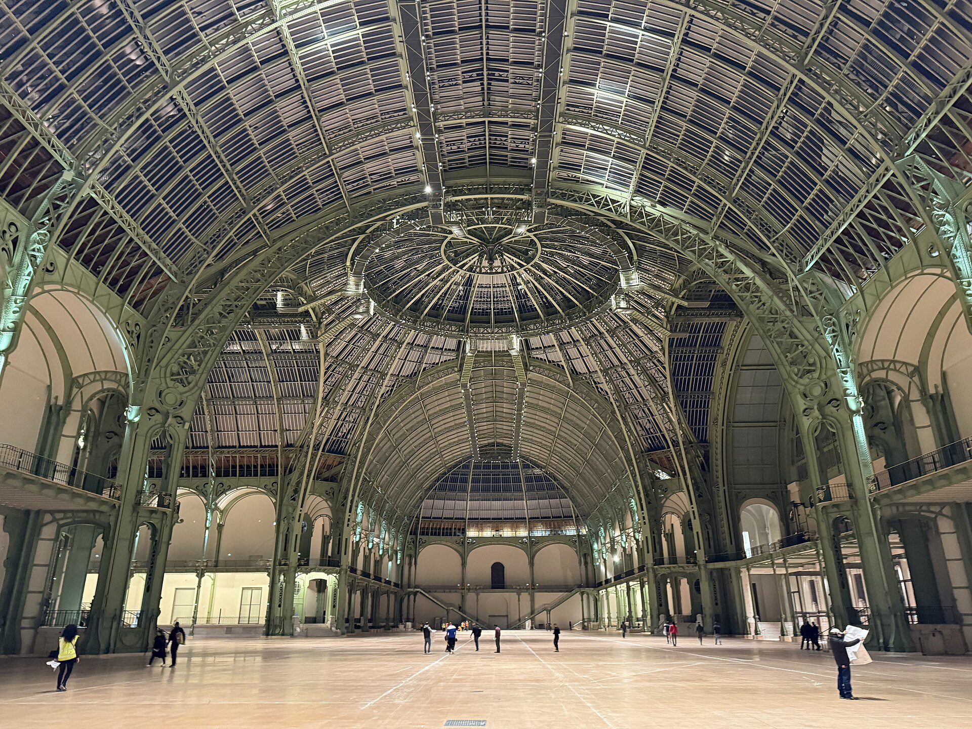 l interno vuoto della nef del grand palais, la struttura in ferro e vetro della volta vista dal basso con la cupola centrale e pochi visitatori sul pavimento