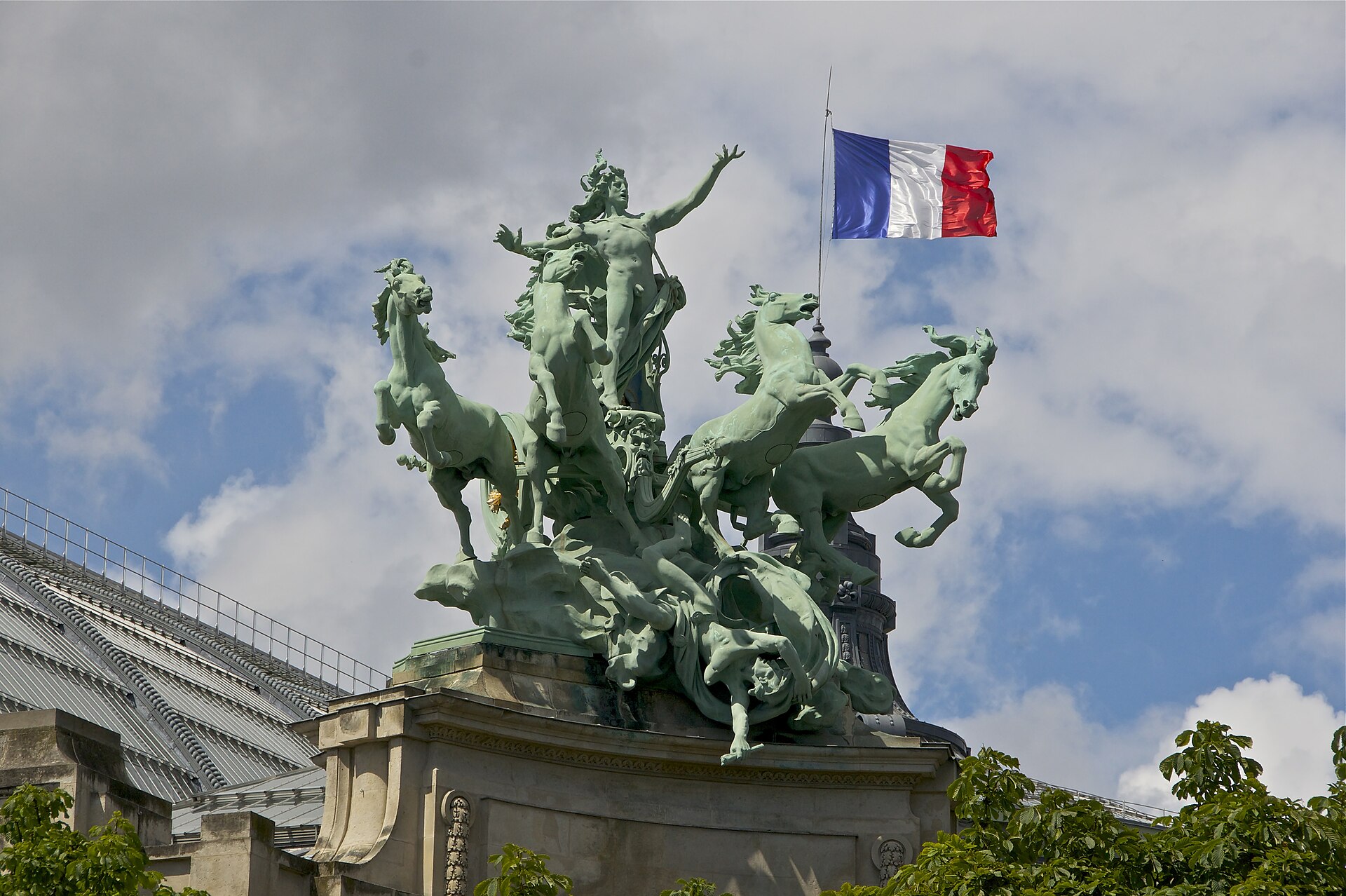 il gruppo bronzeo l harmonie triomphant de la discorde di georges recipon sul tetto del grand palais, la figura alata al centro con le braccia aperte, i cavalli impennati ai lati e la bandiera francese alle spalle