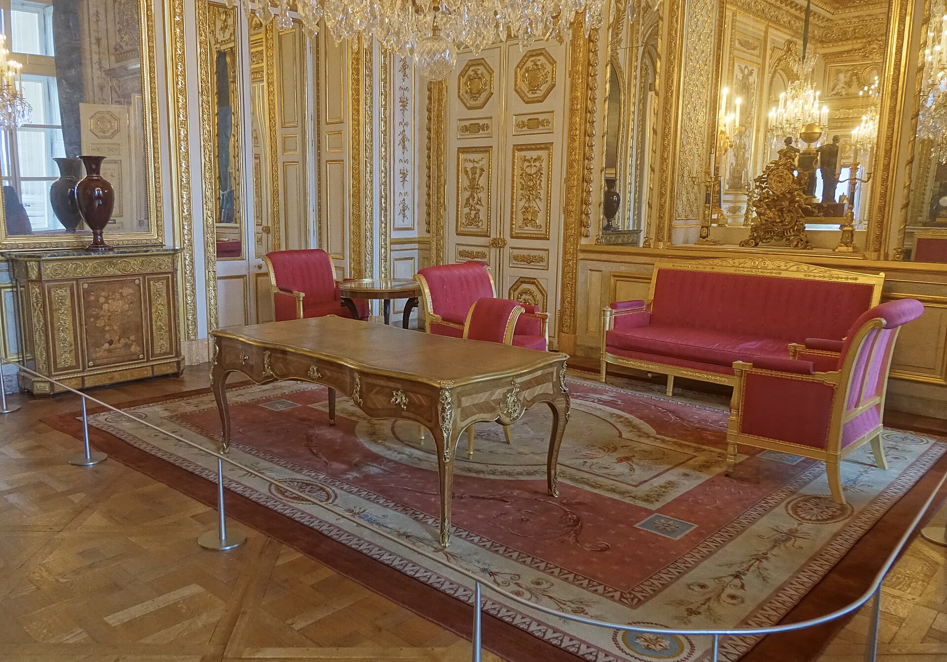 il bureau di victor schoelcher, una scrivania piatta dorata in un salone con divani e poltrone rosse e le boiserie dorate
