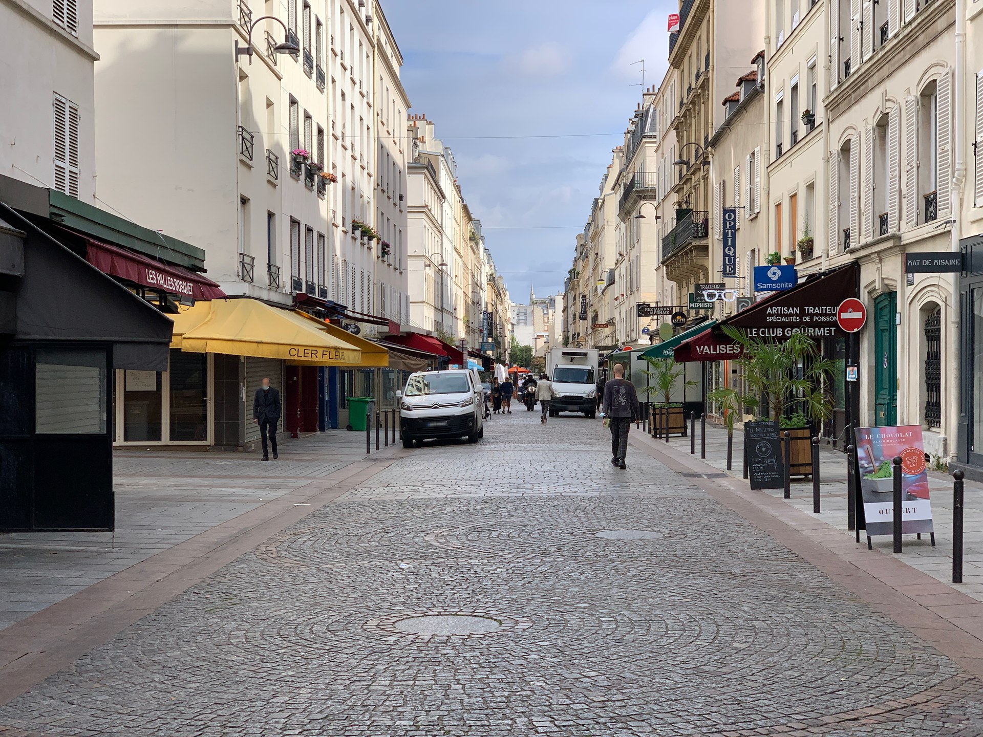 la via pedonale di rue cler nel settimo arrondissement di parigi, con negozi, insegne e tavolini lungo i due lati della strada