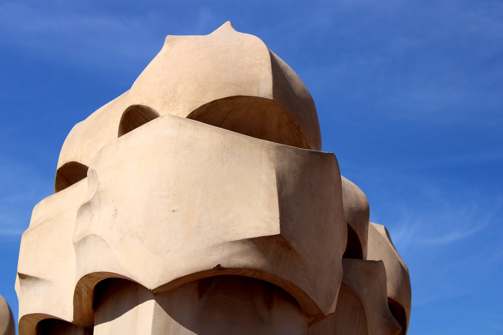 un camino della pedrera di intonaco chiaro, con una forma che ricorda un elmo, contro il cielo blu