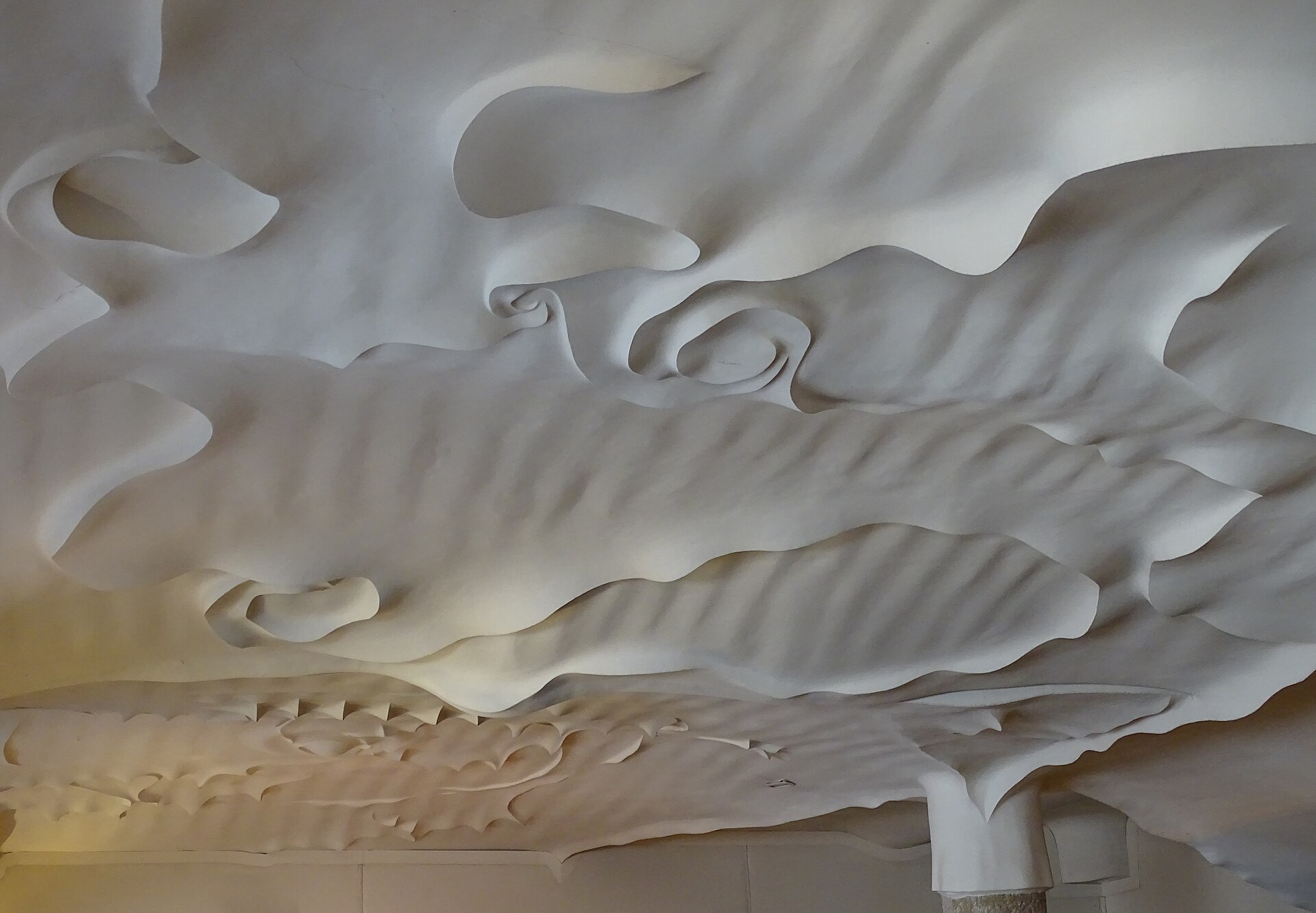 un soffitto in rilievo della pedrera, con onde e spirali di stucco bianco