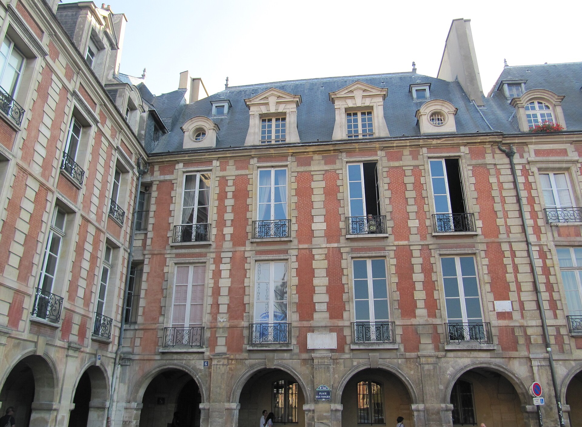 la facciata al numero 6 di place des vosges a parigi, di mattoni rossi e pietra chiara, con i portici in basso e il tetto di ardesia con le lucernaie
