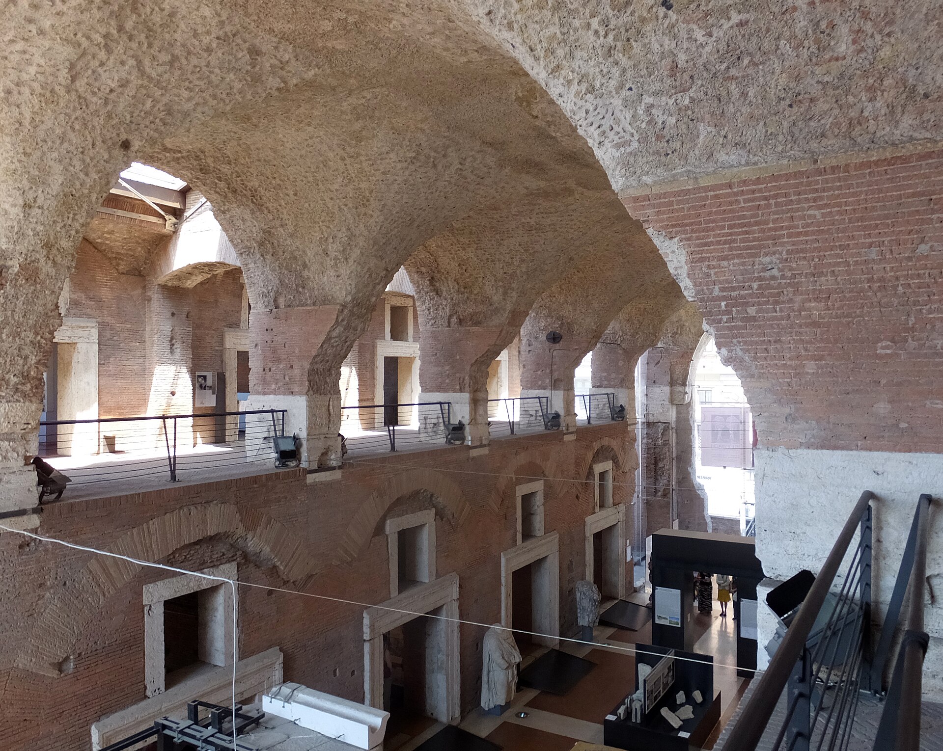 l’interno della grande aula dei mercati di traiano, con le volte a crociera in conglomerato grezzo, il ballatoio in legno e le tabernae incorniciate in travertino