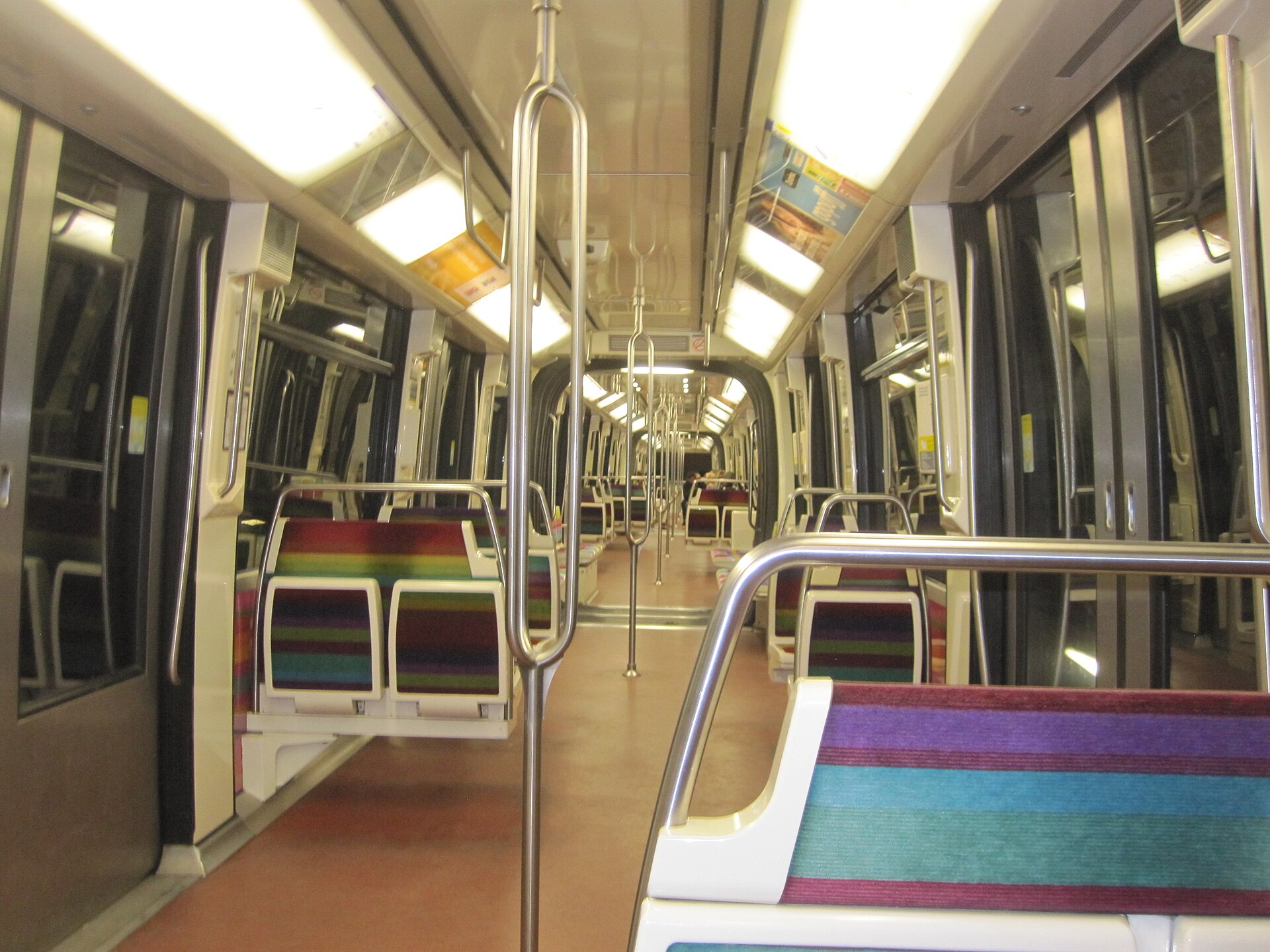 interno vuoto di una carrozza della linea 1 della metropolitana di parigi, con sedili a righe colorate e barre di sostegno in metallo lucido