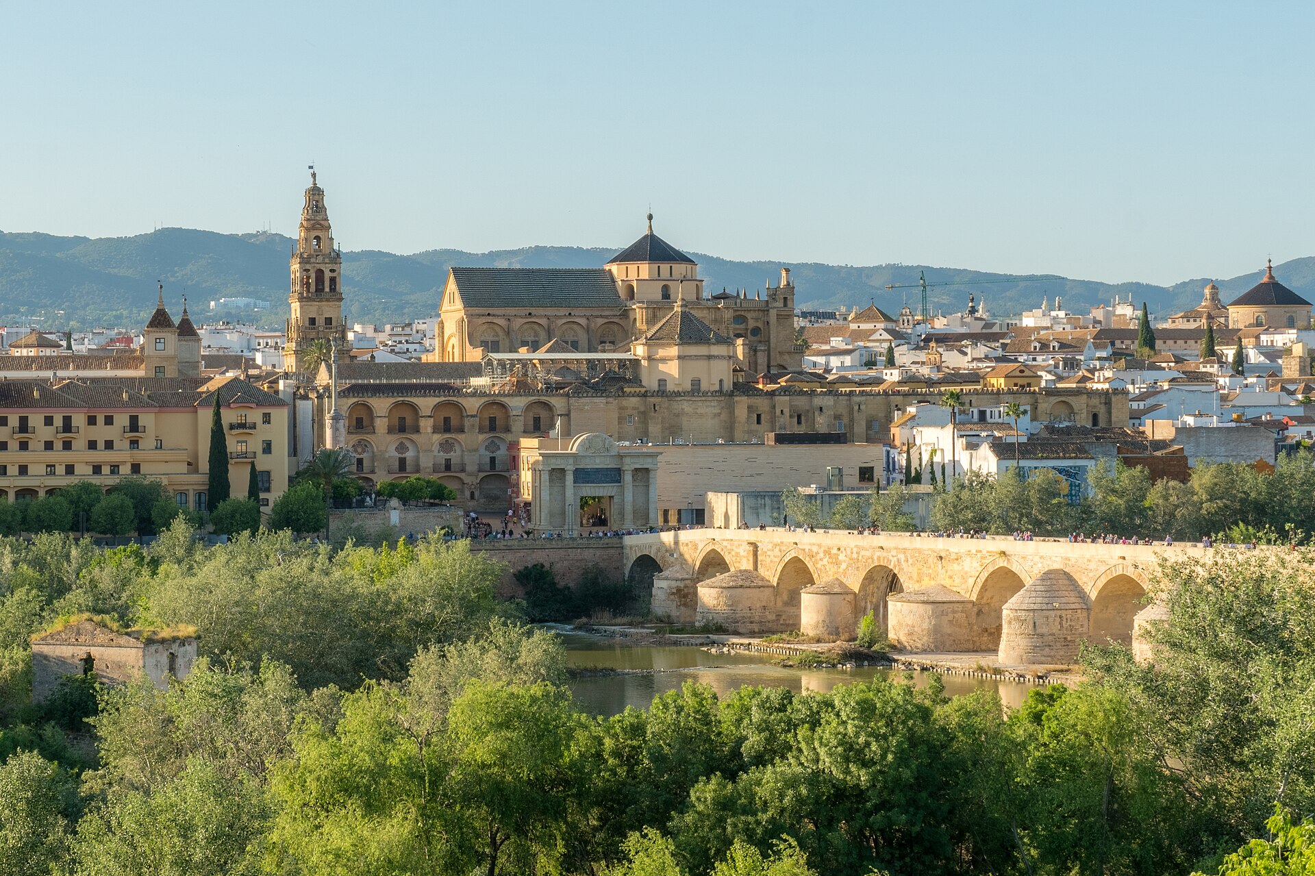 la mezquita di cordoba vista dal fiume guadalquivir, con il campanile, la cupola della cattedrale, il ponte romano ad archi e il verde in primo piano