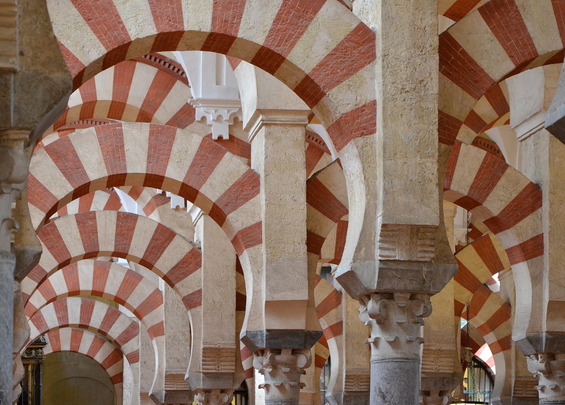 la sala delle colonne della mezquita di cordoba, con file di archi a ferro di cavallo a strisce rosse e chiare che si perdono in profondità