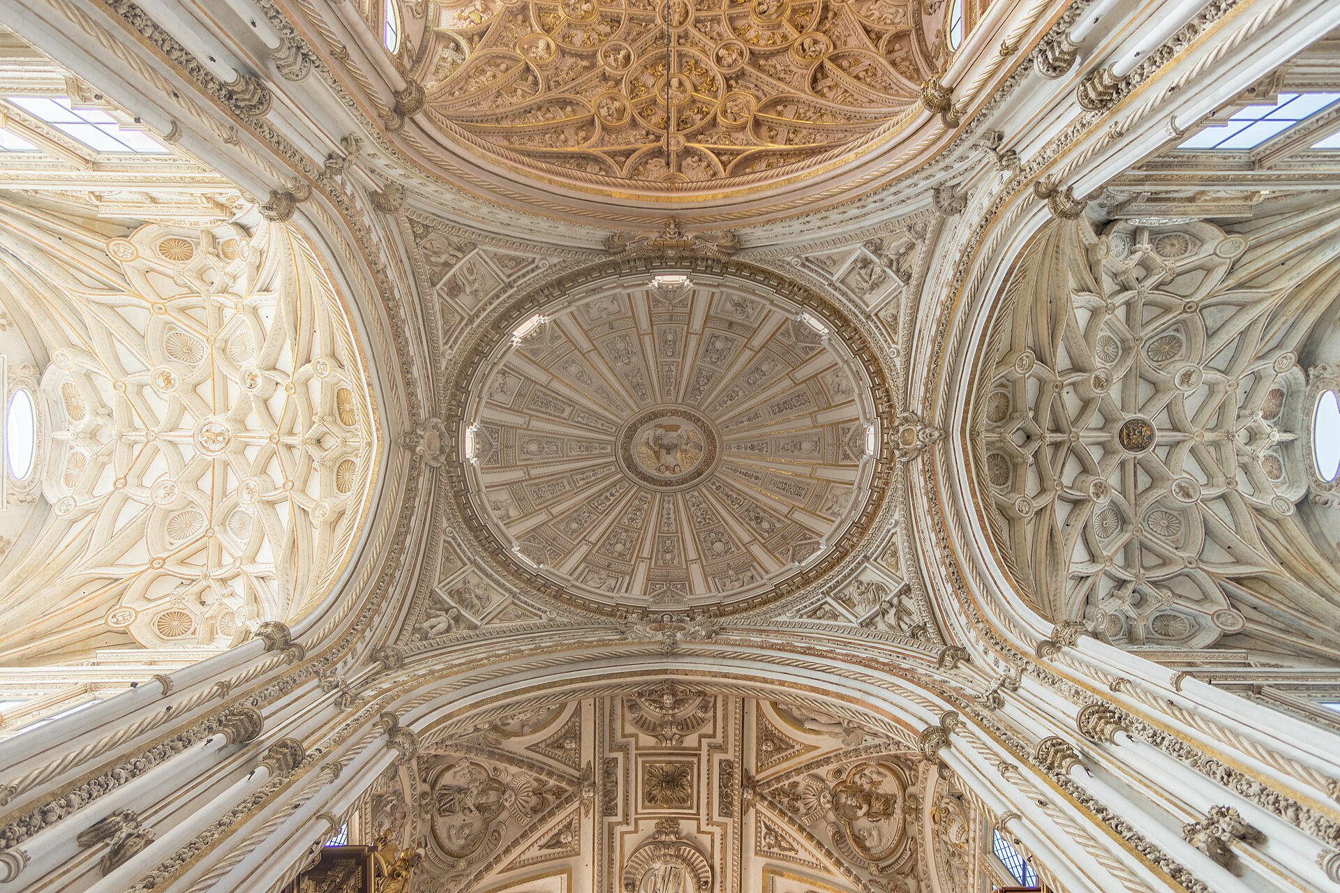 la volta del transetto della cattedrale dentro la mezquita di cordoba, bianca e decorata da sculture e costoloni attorno a un ovale centrale