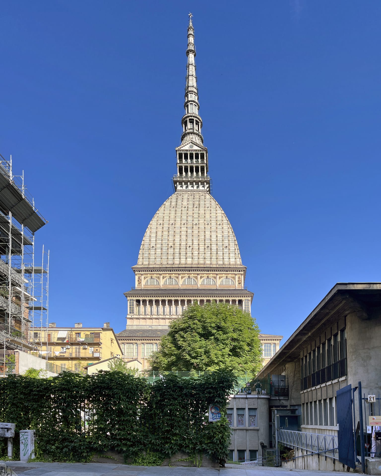 the mole antonelliana in turin seen whole, with its scaled dome and spire against a blue sky