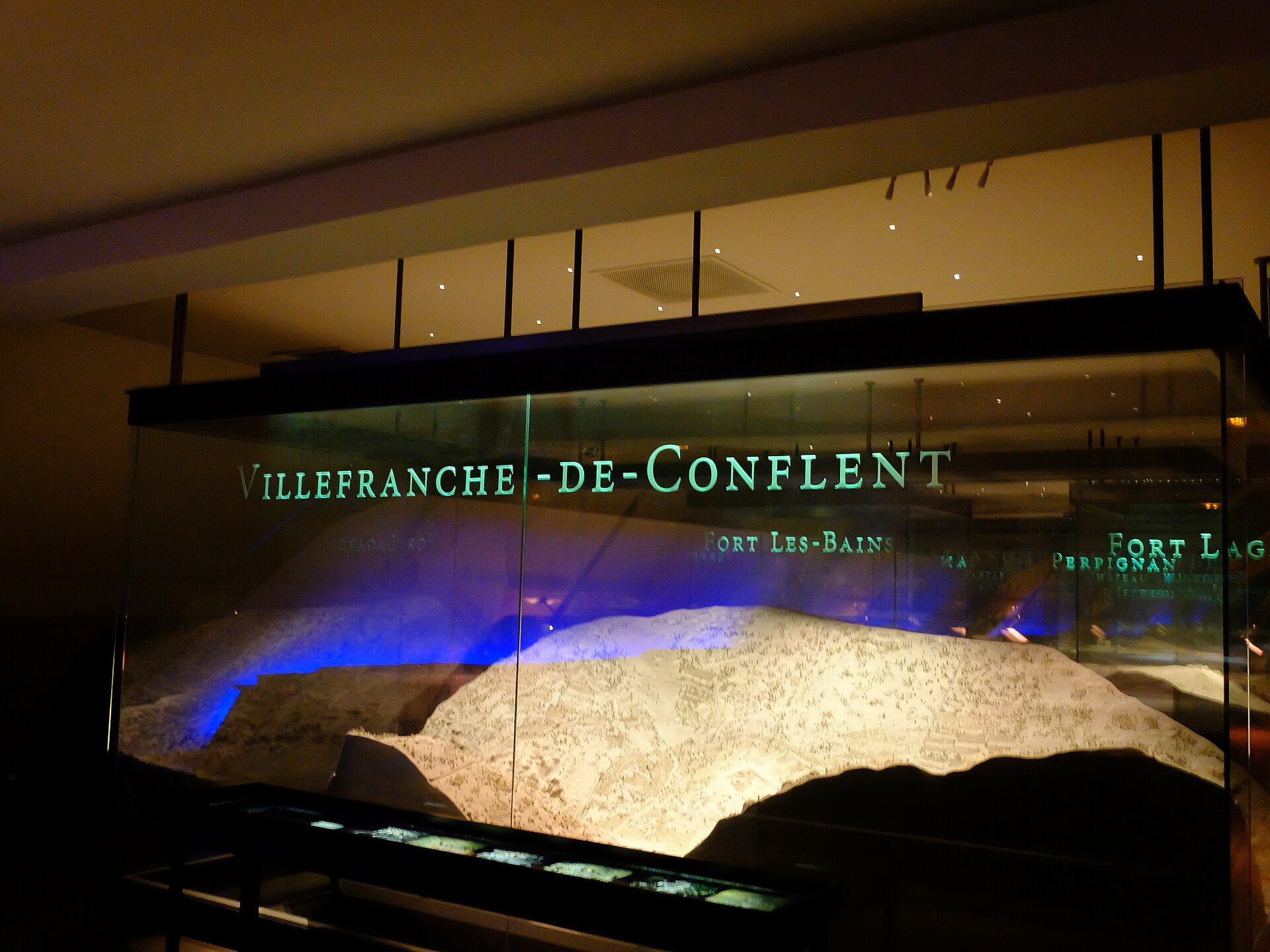 une maquette du musee des plans-reliefs aux invalides, la ville fortifiee de villefranche-de-conflent avec ses remparts et les montagnes autour, dans une vitrine eclairee dans le noir