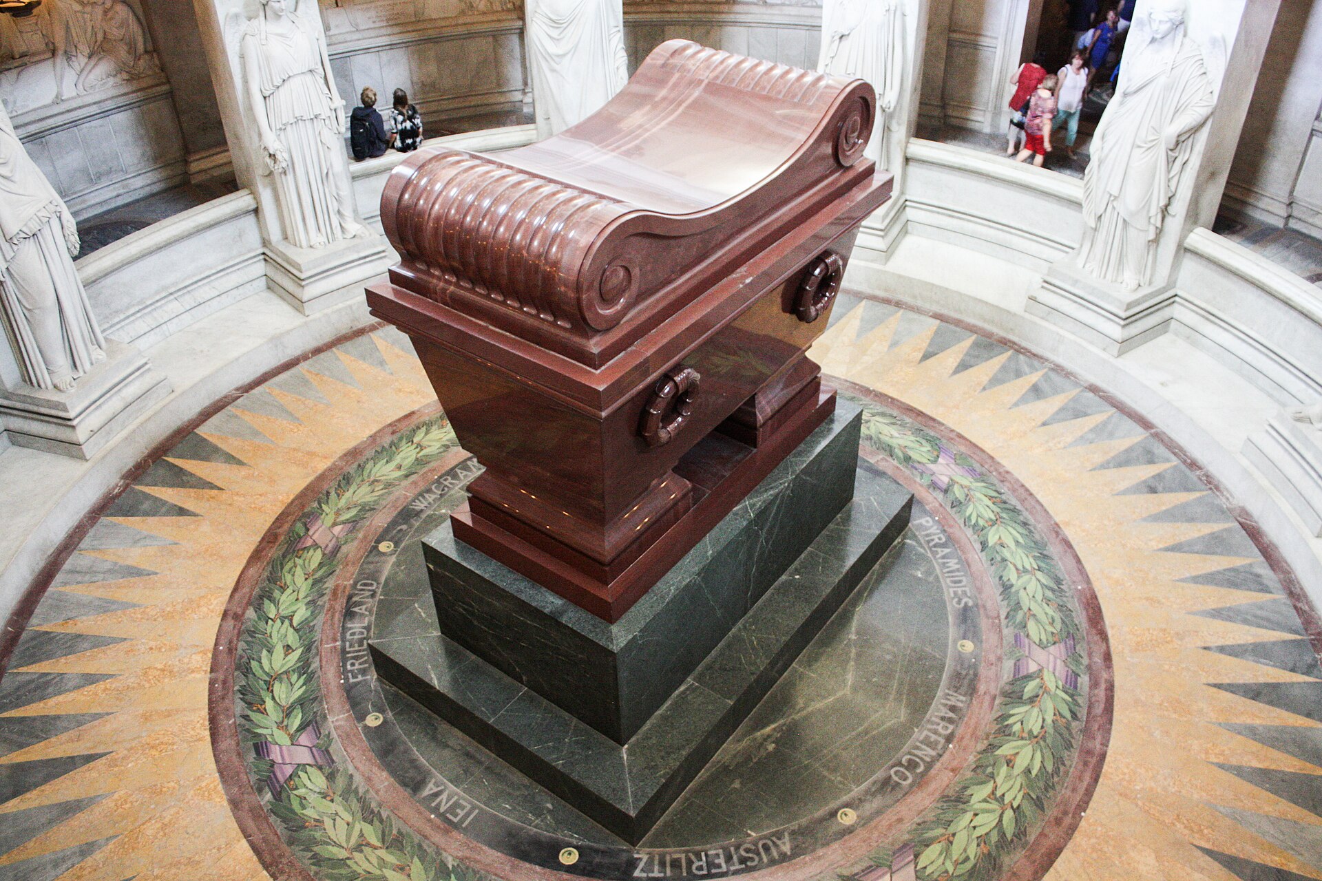 le tombeau de napoleon aux invalides, le grand sarcophage de pierre rouge sur un socle de pierre verte, au centre de la crypte circulaire au sol de mosaique