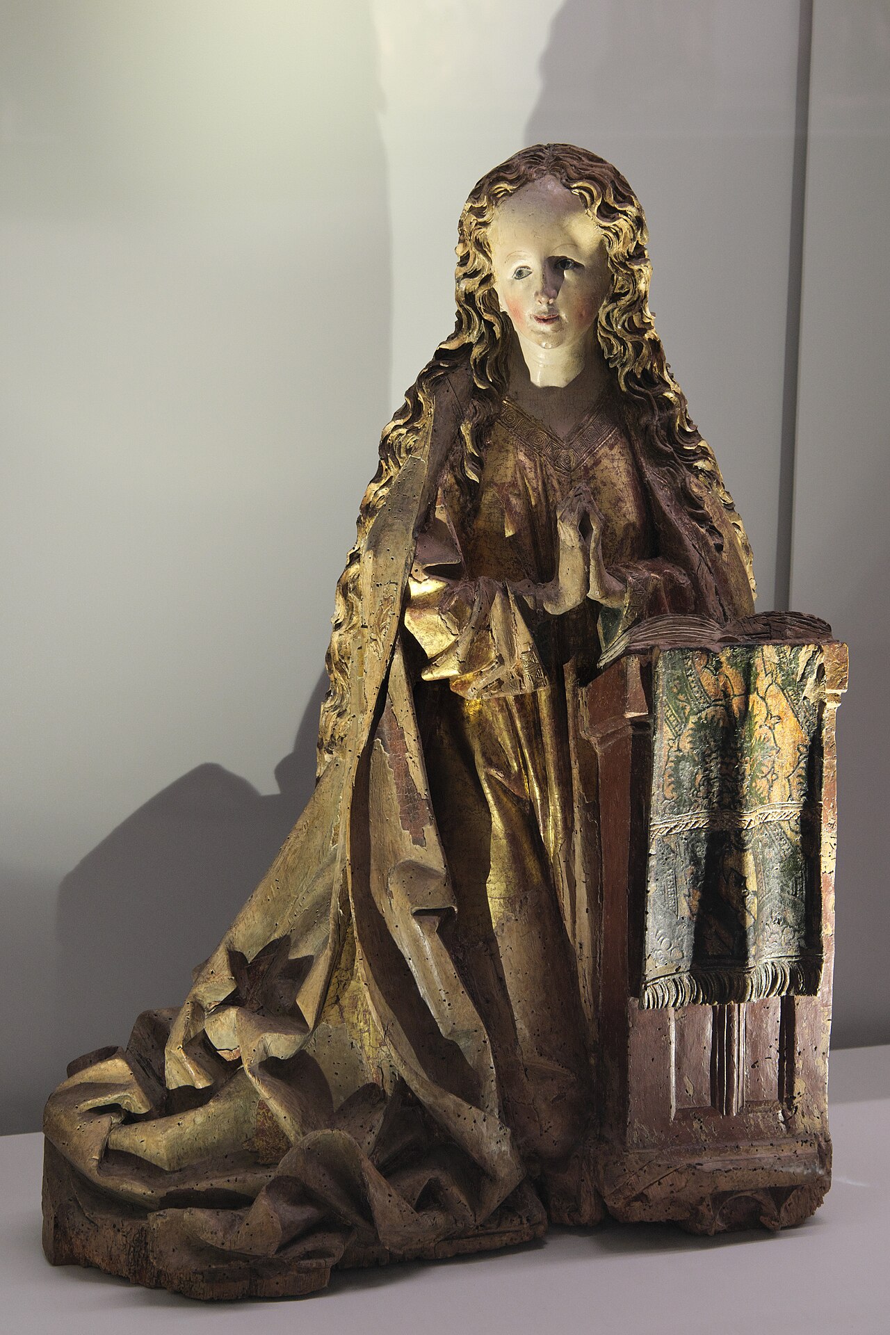la vierge d une annonciation en bois sculpte et dore, vers 1500, agenouillee les mains jointes devant un lutrin couvert d un drap