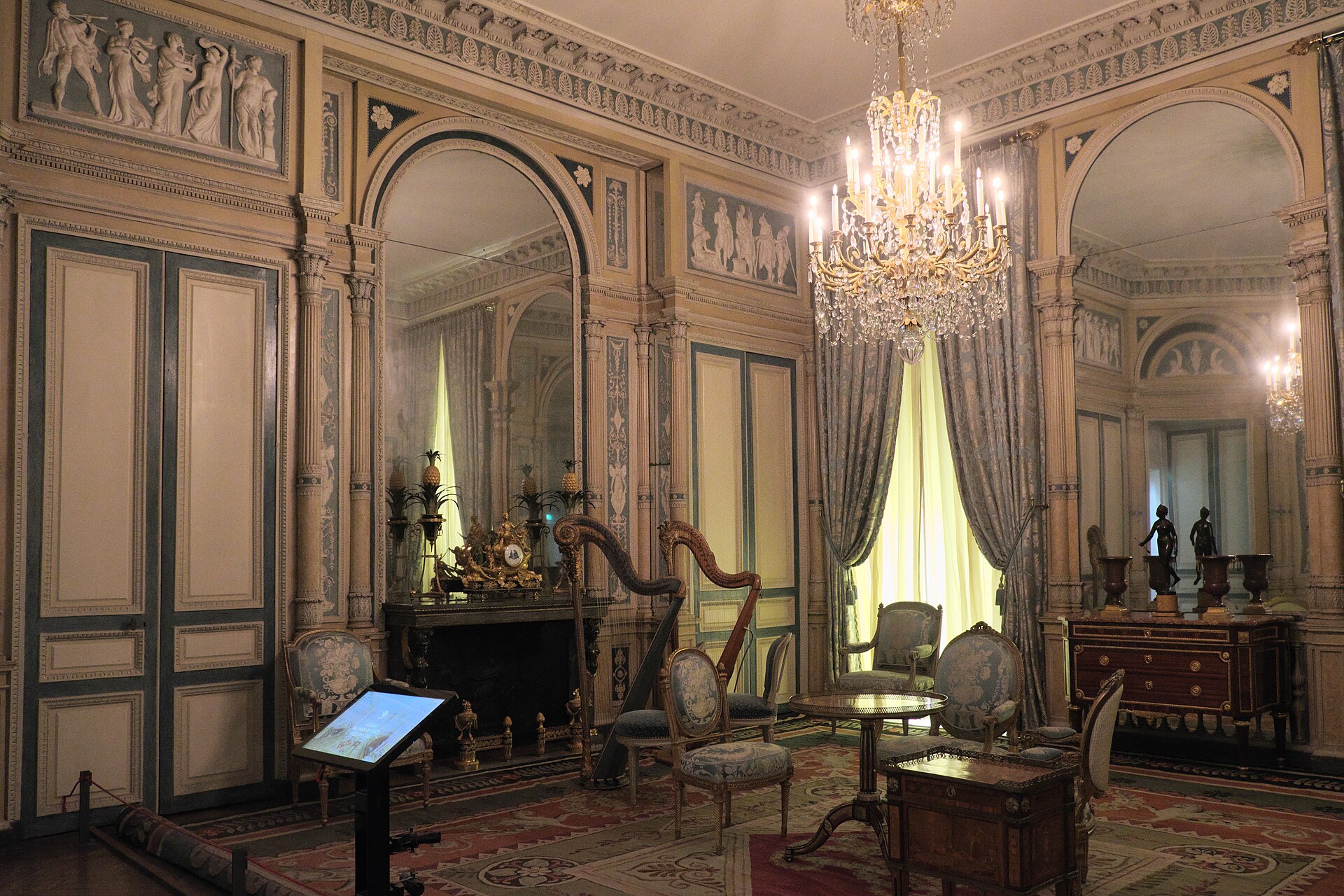 le salon de l hotel de serres remonte au musee des arts decoratifs, avec les boiseries claires, les miroirs en arc, le lustre de cristal, une harpe et les chaises dorees