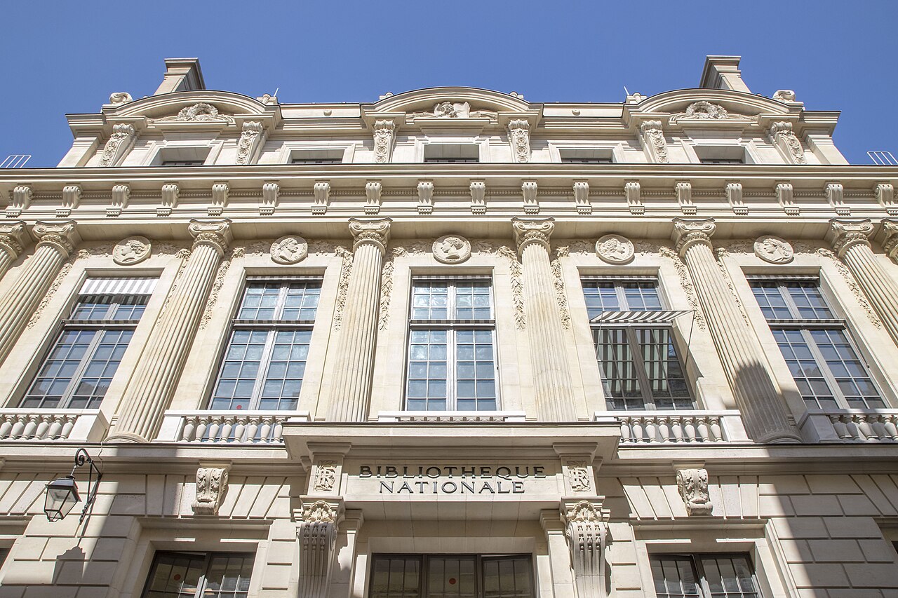 la facciata di pietra chiara della bibliotheque nationale vista dal basso, con le paraste scanalate, i medaglioni a ritratto fra i capitelli e l iscrizione bibliotheque nationale scolpita sopra l ingresso