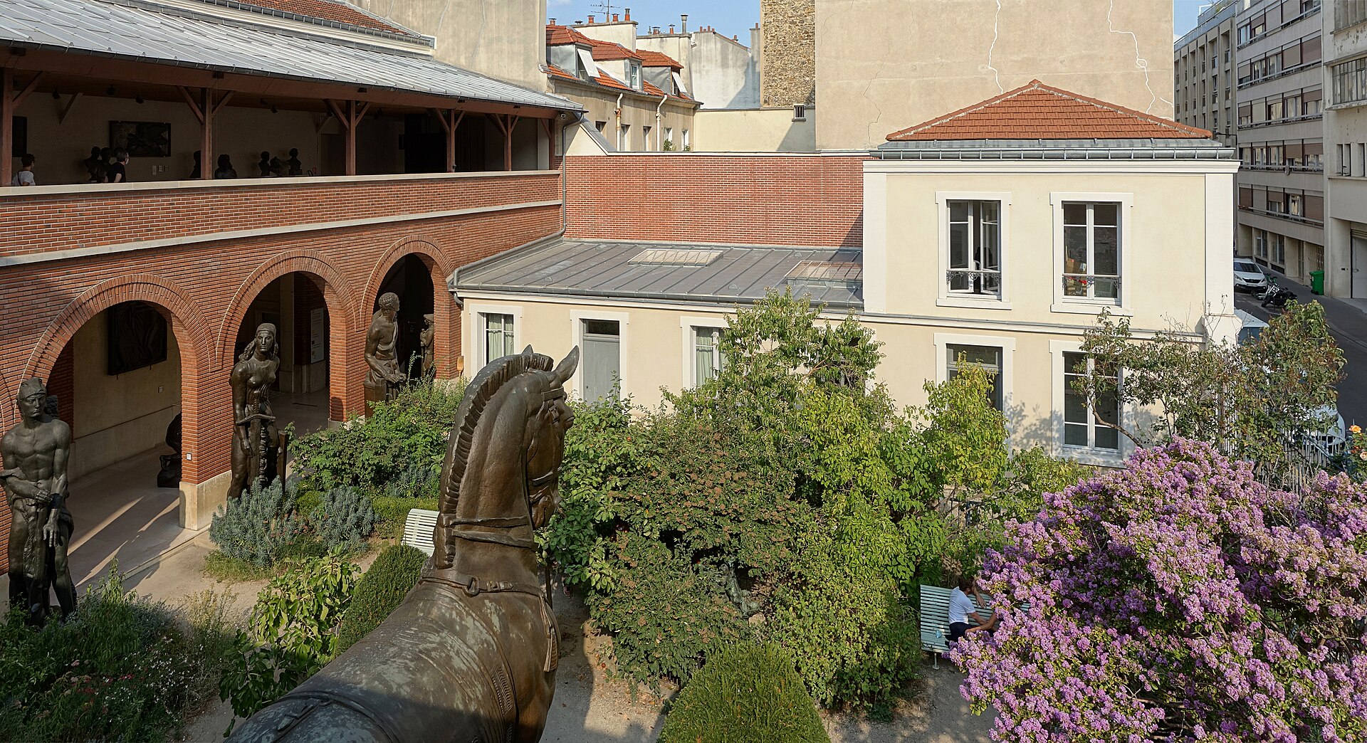 le jardin du musee bourdelle vu d en haut, avec la loggia de brique rouge aux arcades pleines de sculptures et une grande tete de cheval en bronze au premier plan