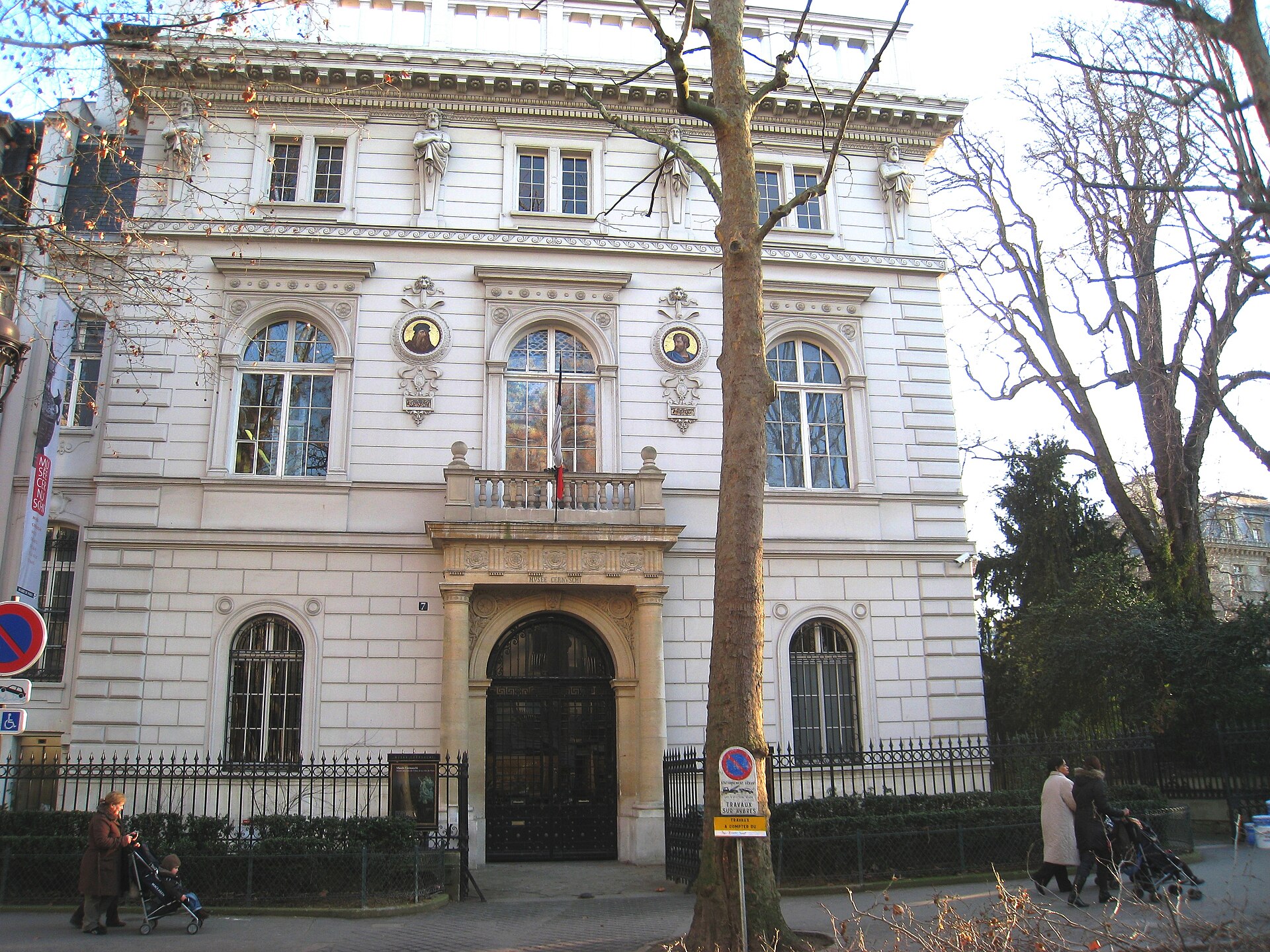 la facciata bianca della villa del musee cernuschi in avenue velasquez, con il grande portale ad arco, due medaglioni a mosaico e le statue sotto il cornicione
