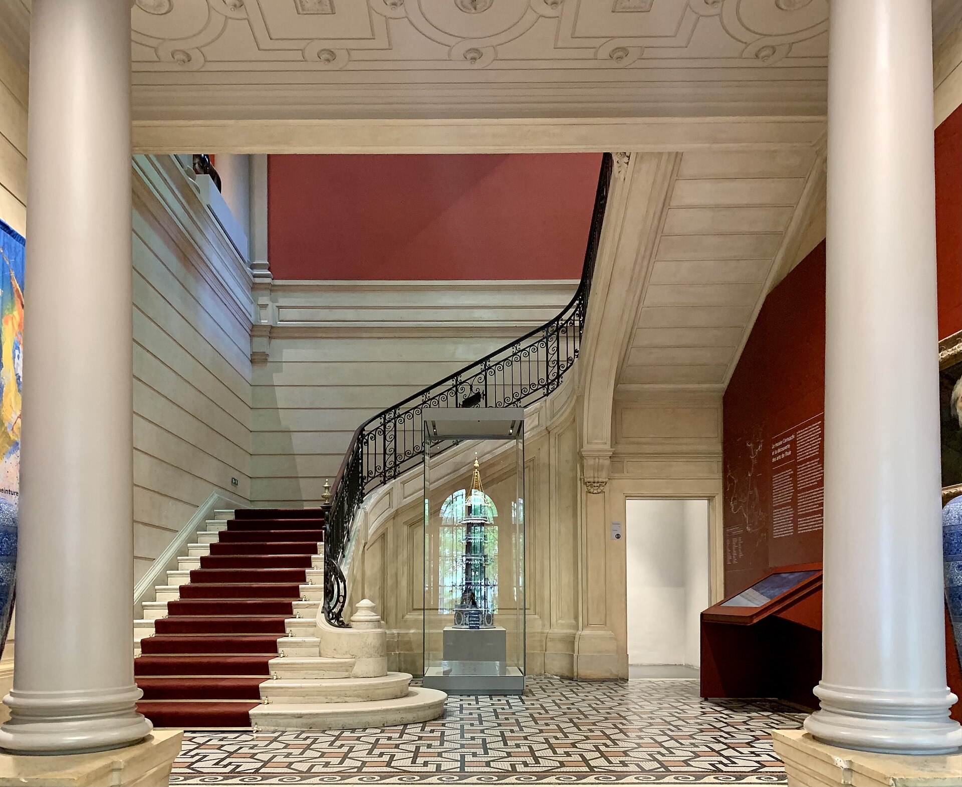 lo scalone d interno del musee cernuschi con il tappeto rosso, la ringhiera in ferro battuto e il pavimento a mosaico geometrico
