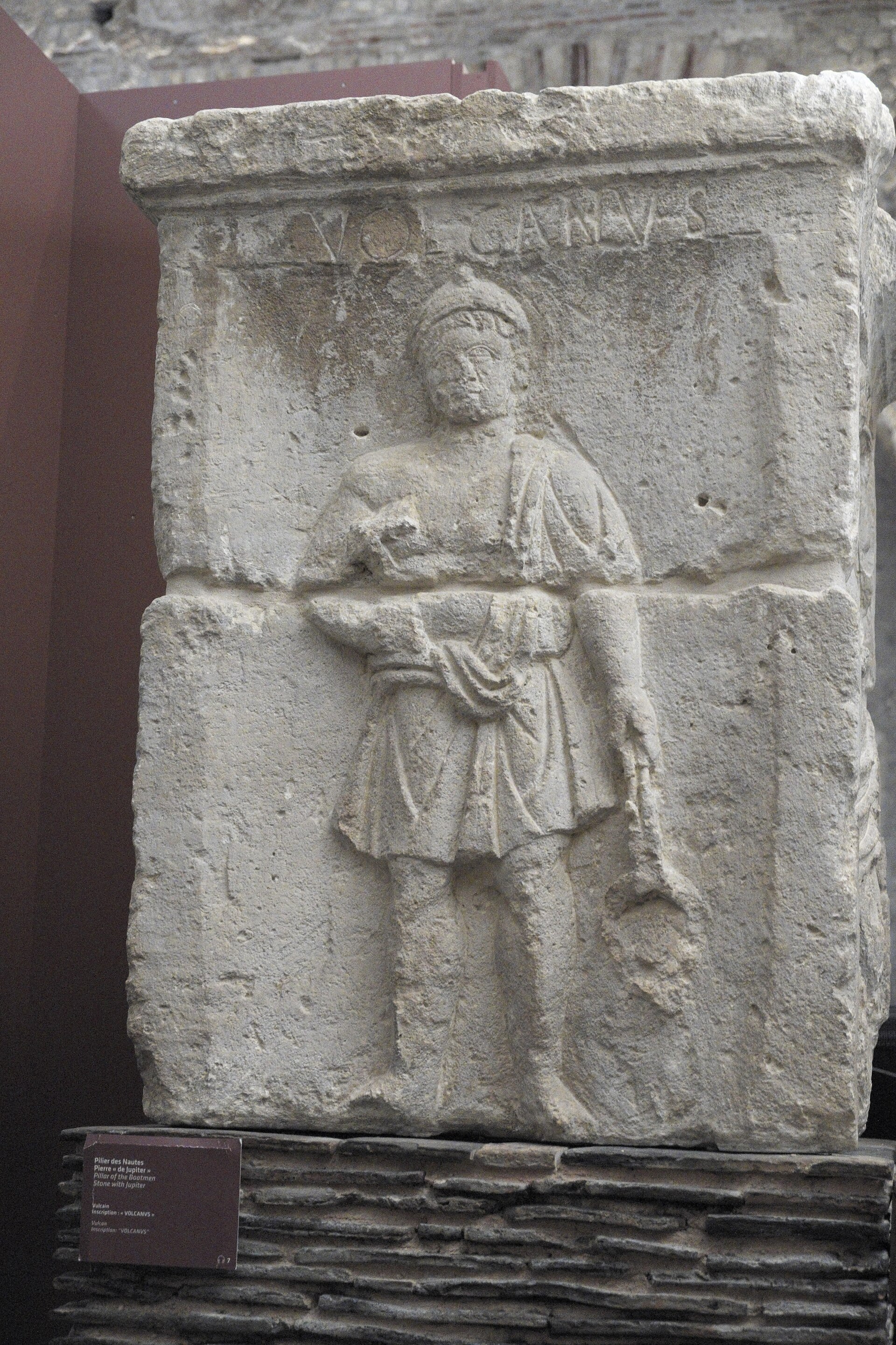 a block of the pillar of the boatmen at the musee de cluny, with volcanvs cut above the figure of vulcan in a short tunic and a conical cap