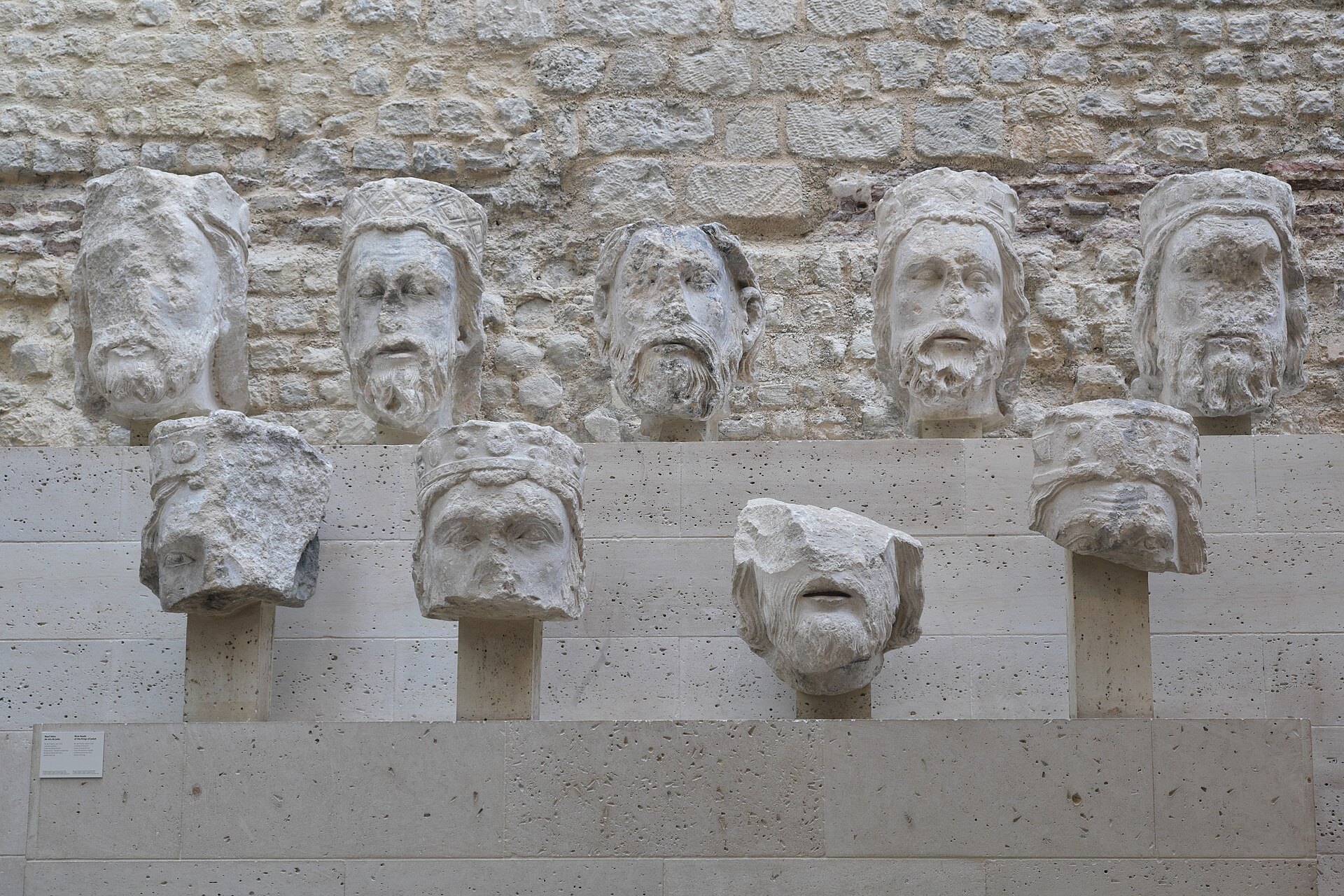nine stone heads of the kings of judah from notre-dame set on two rows of brackets against a rough stone wall at the musee de cluny