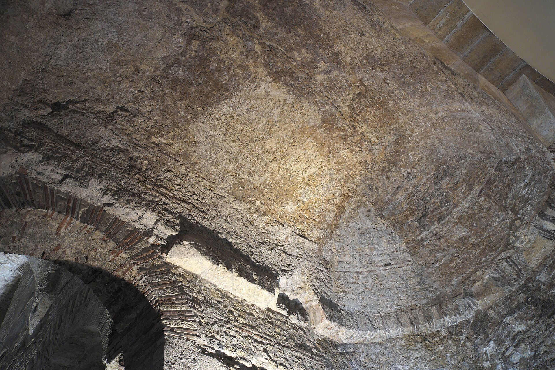 the roman vault of the frigidarium of the cluny baths seen from below, in bare stone and brick, with the brick arch springing from the corner pier