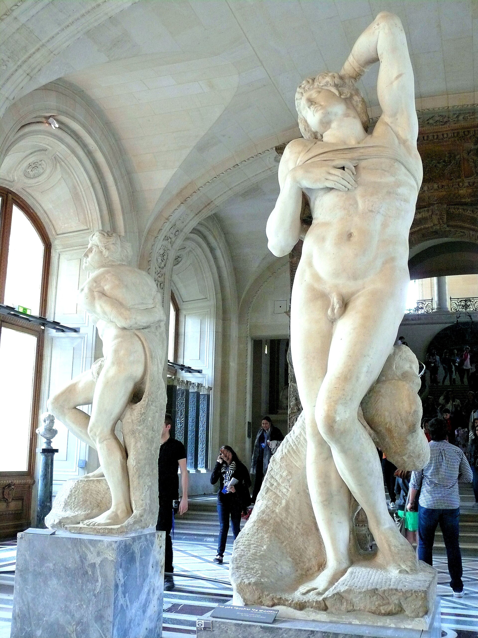 la galerie michel-ange du louvre avec l esclave rebelle a gauche, le buste tordu vers l arriere, et l esclave mourant a droite, le bras leve derriere la tete