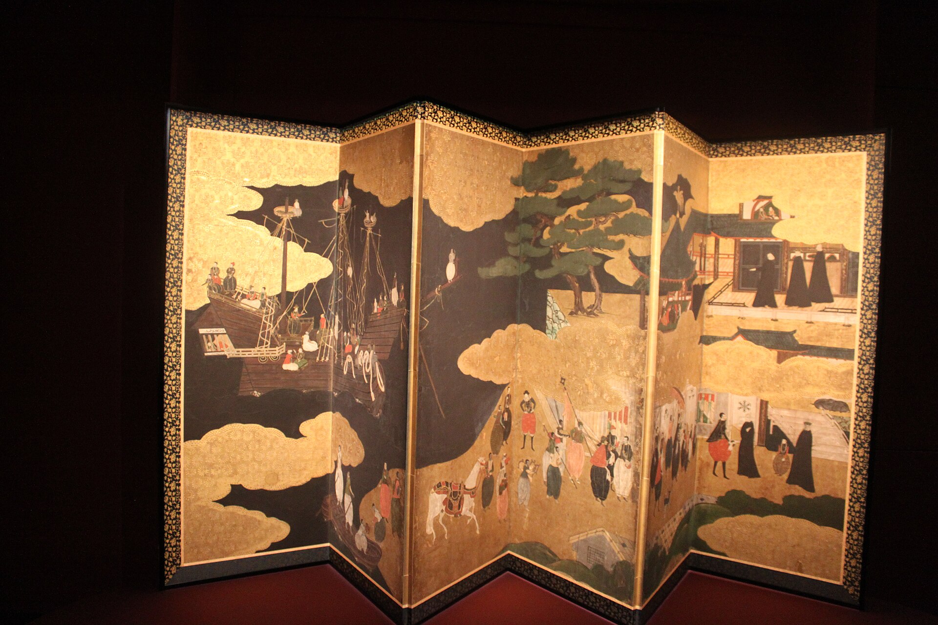 il paravento nanban a sei ante del musee guimet, su fondo d oro una nave portoghese a sinistra, un corteo con cavallo al centro e gesuiti in nero davanti a un edificio a destra