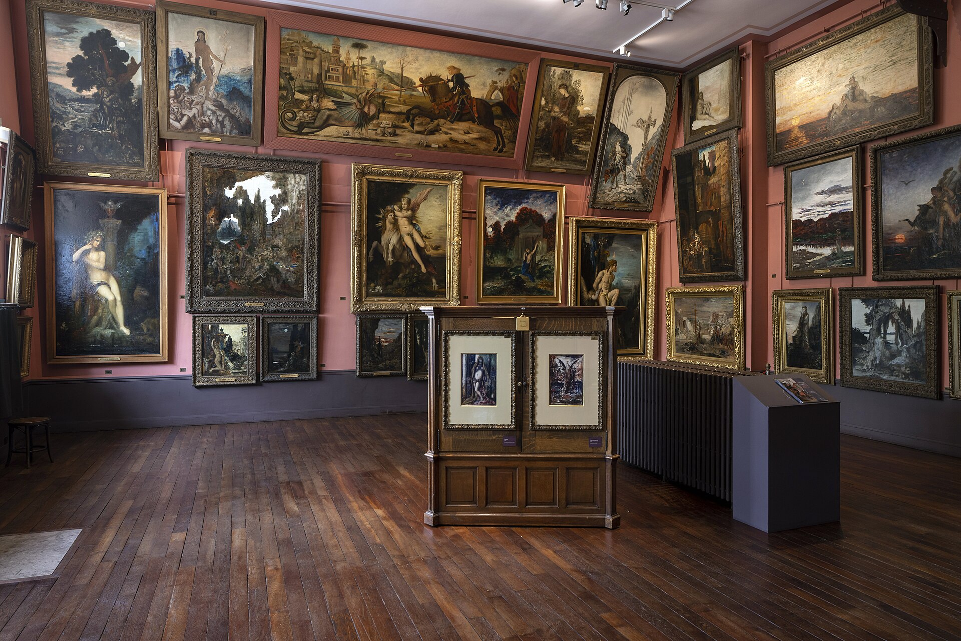 l atelier del musee gustave moreau con le pareti rosa coperte di quadri incorniciati dal pavimento al soffitto e il pavimento di legno scuro