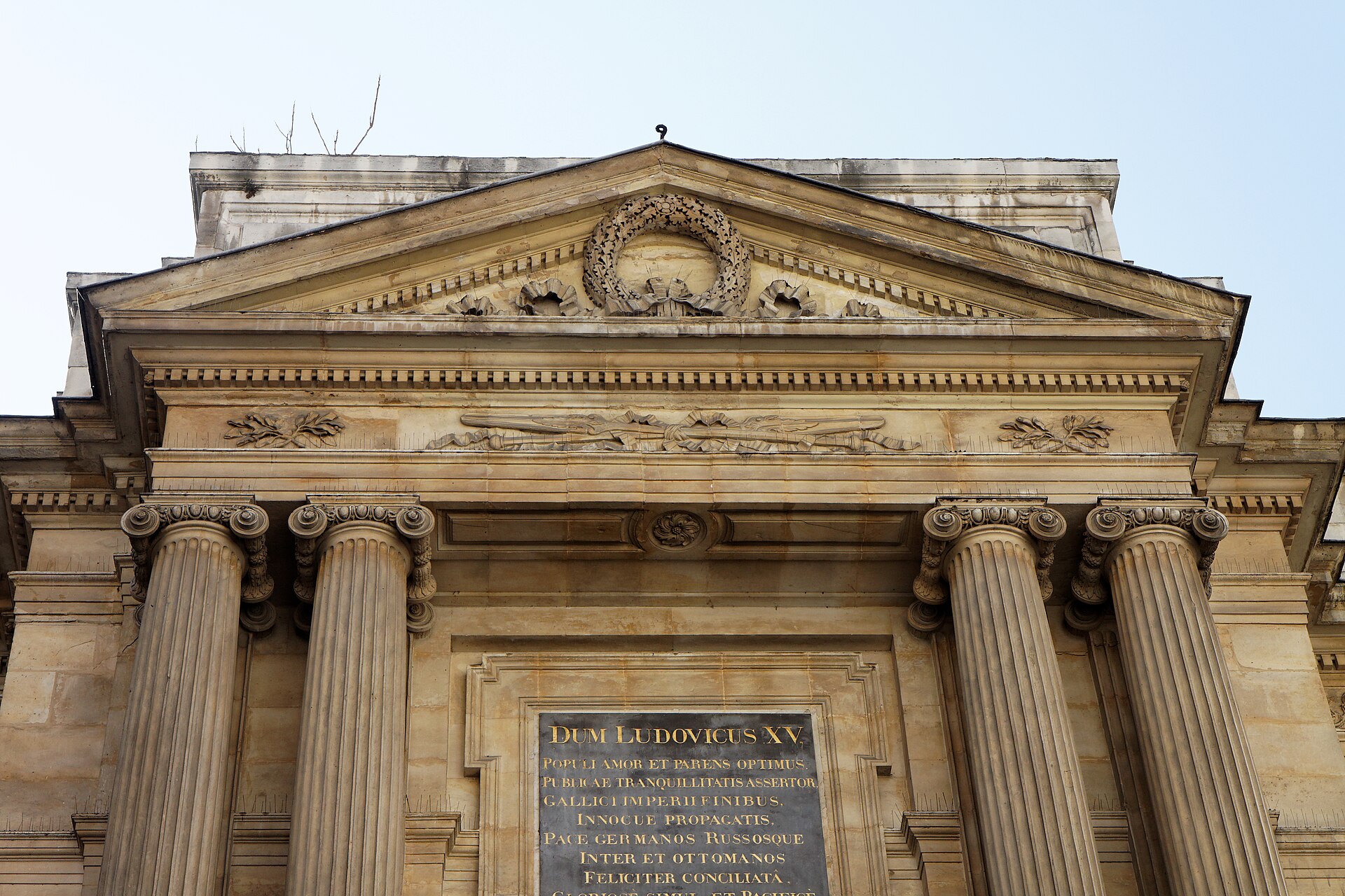 le fronton de la fontaine des quatre-saisons rue de grenelle, avec les colonnes ioniques et la plaque de marbre noir a l inscription latine en lettres dorees