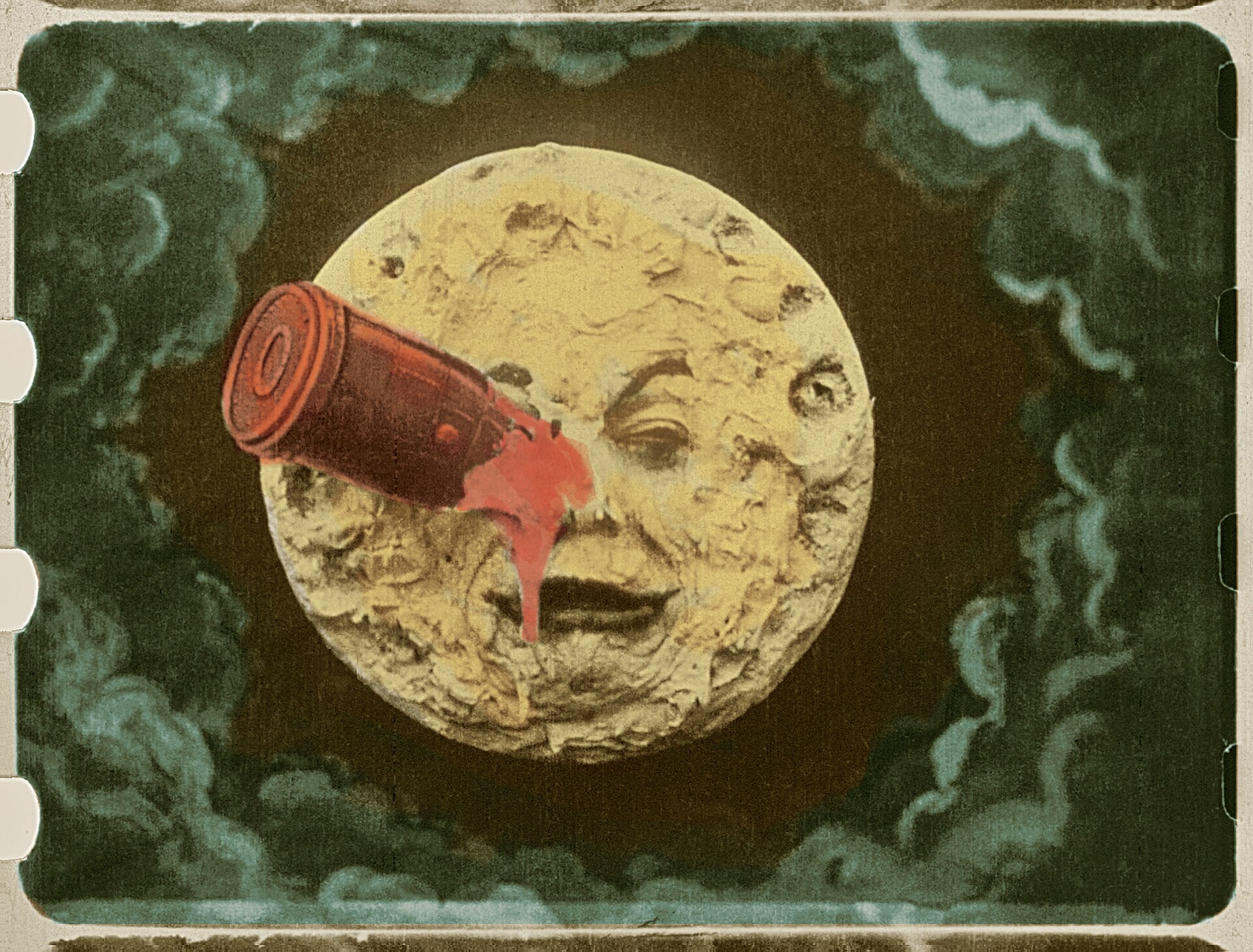 fotogramma colorato a mano del voyage dans la lune con la faccia della luna gialla e la capsula rossa conficcata in un occhio, le perforazioni della pellicola visibili ai lati