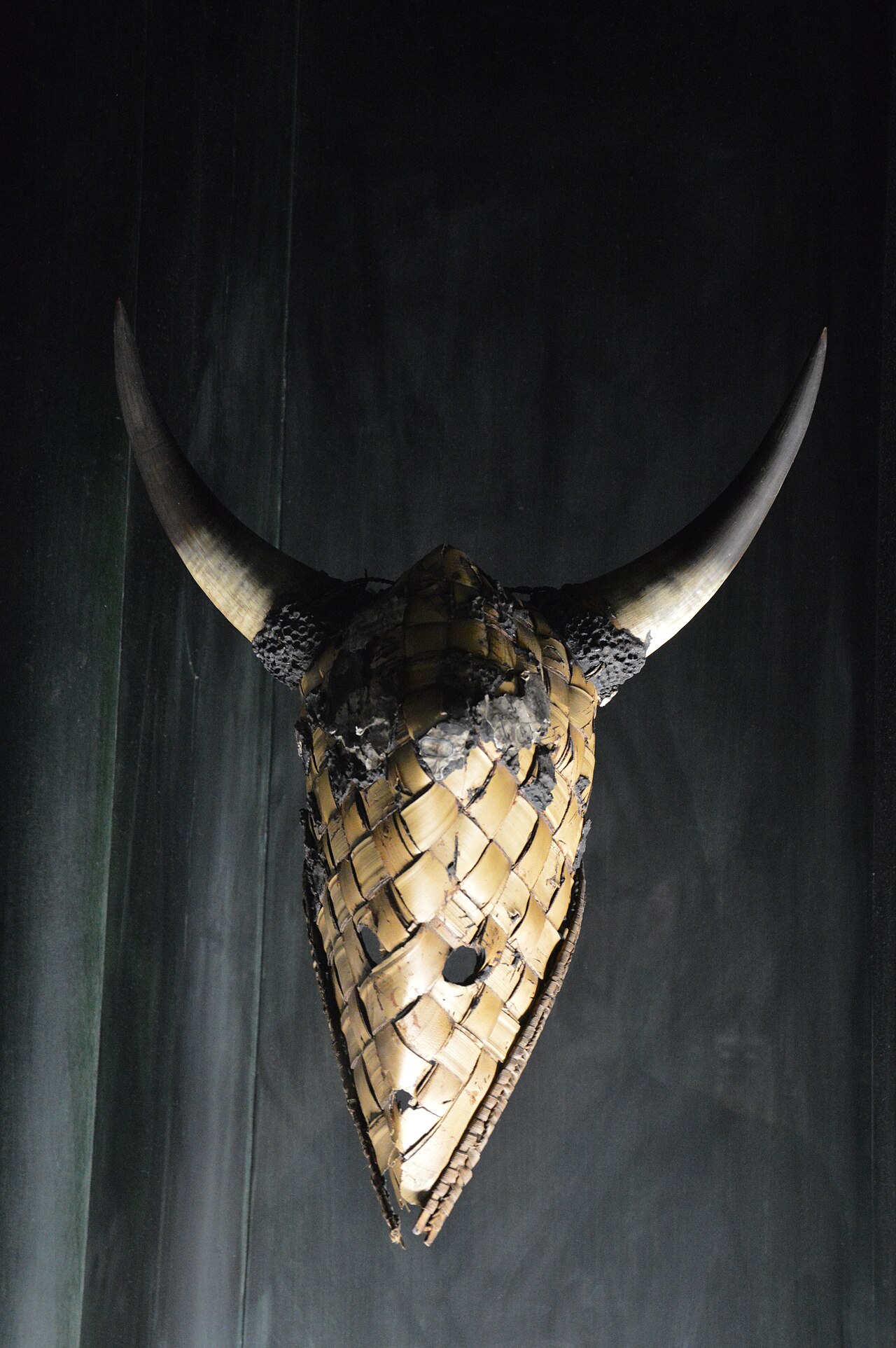 le masque kebul de casamance au musee du quai branly, un masque de fibres tressees en forme de long museau avec deux grandes cornes recourbees, sur un fond sombre