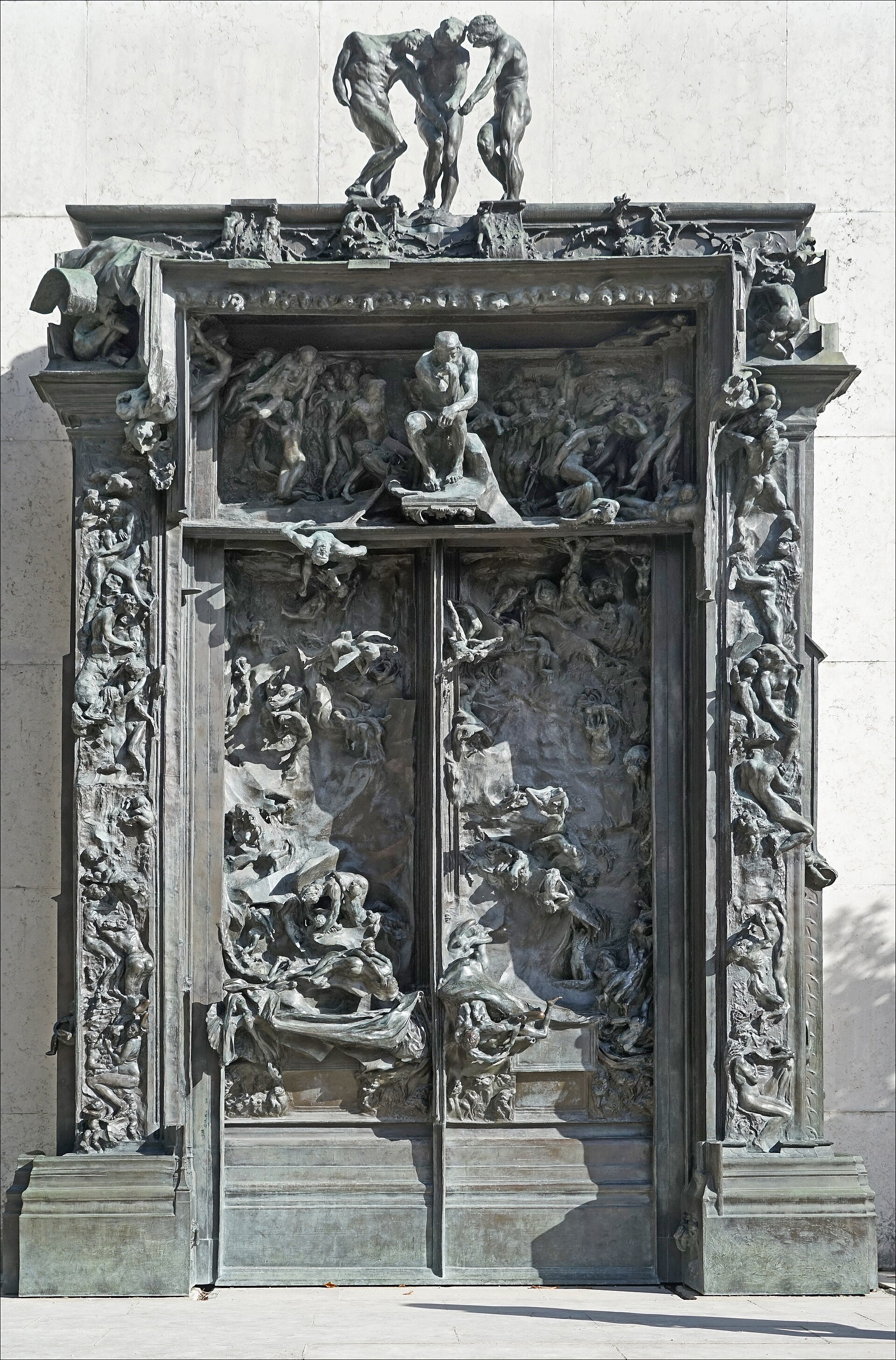 la porte de l enfer de rodin, un grand portail de bronze couvert de figures qui se tordent, avec le penseur au centre au-dessus des battants et les trois ombres au sommet
