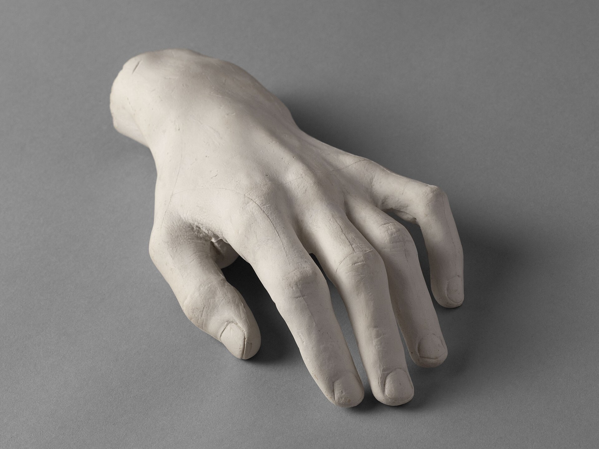 il calco in gesso bianco della mano sinistra di chopin su fondo grigio, con le dita leggermente incurvate