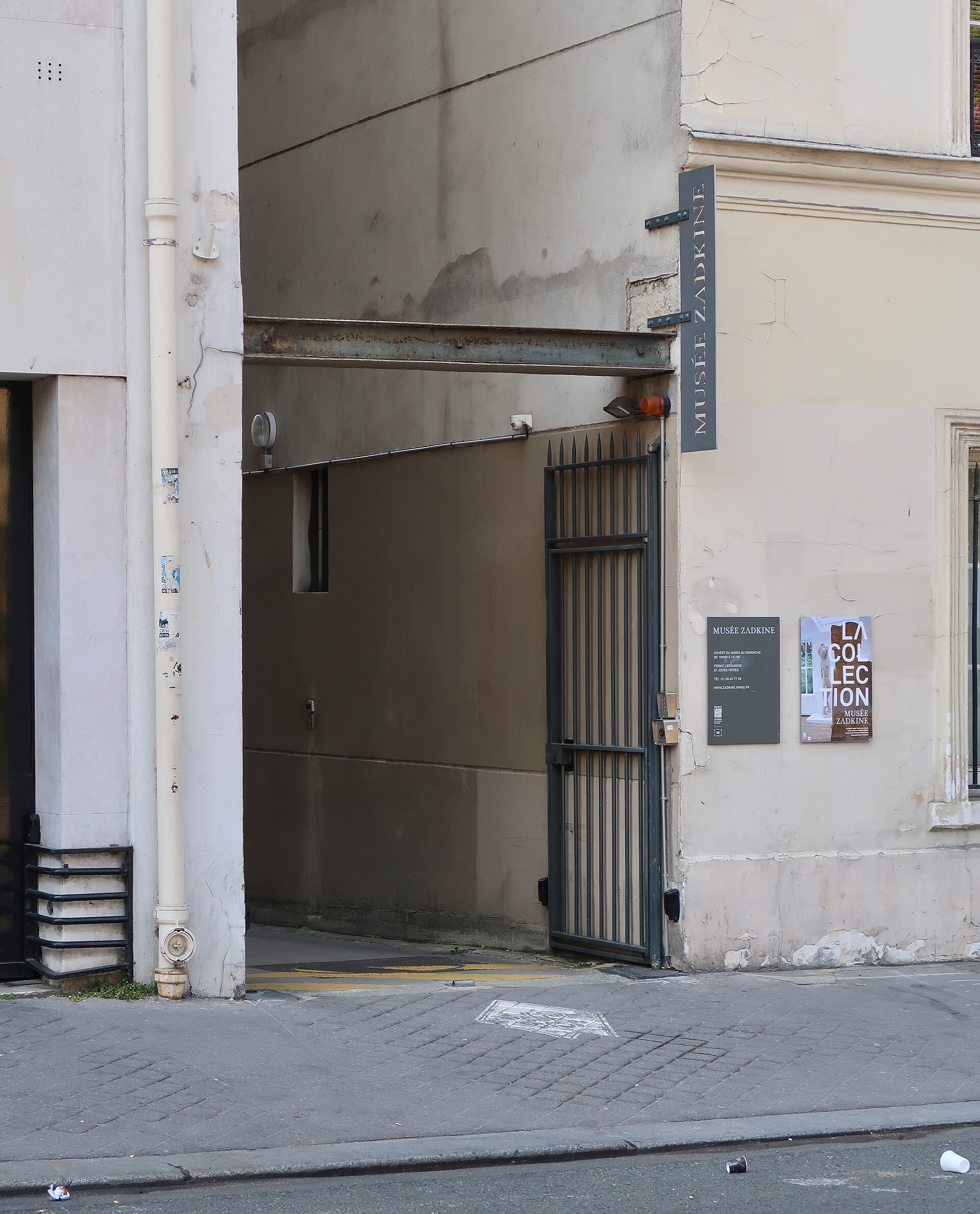 l entree du musee zadkine rue d assas, un passage etroit entre deux immeubles avec la grille de fer et l enseigne perpendiculaire au mur