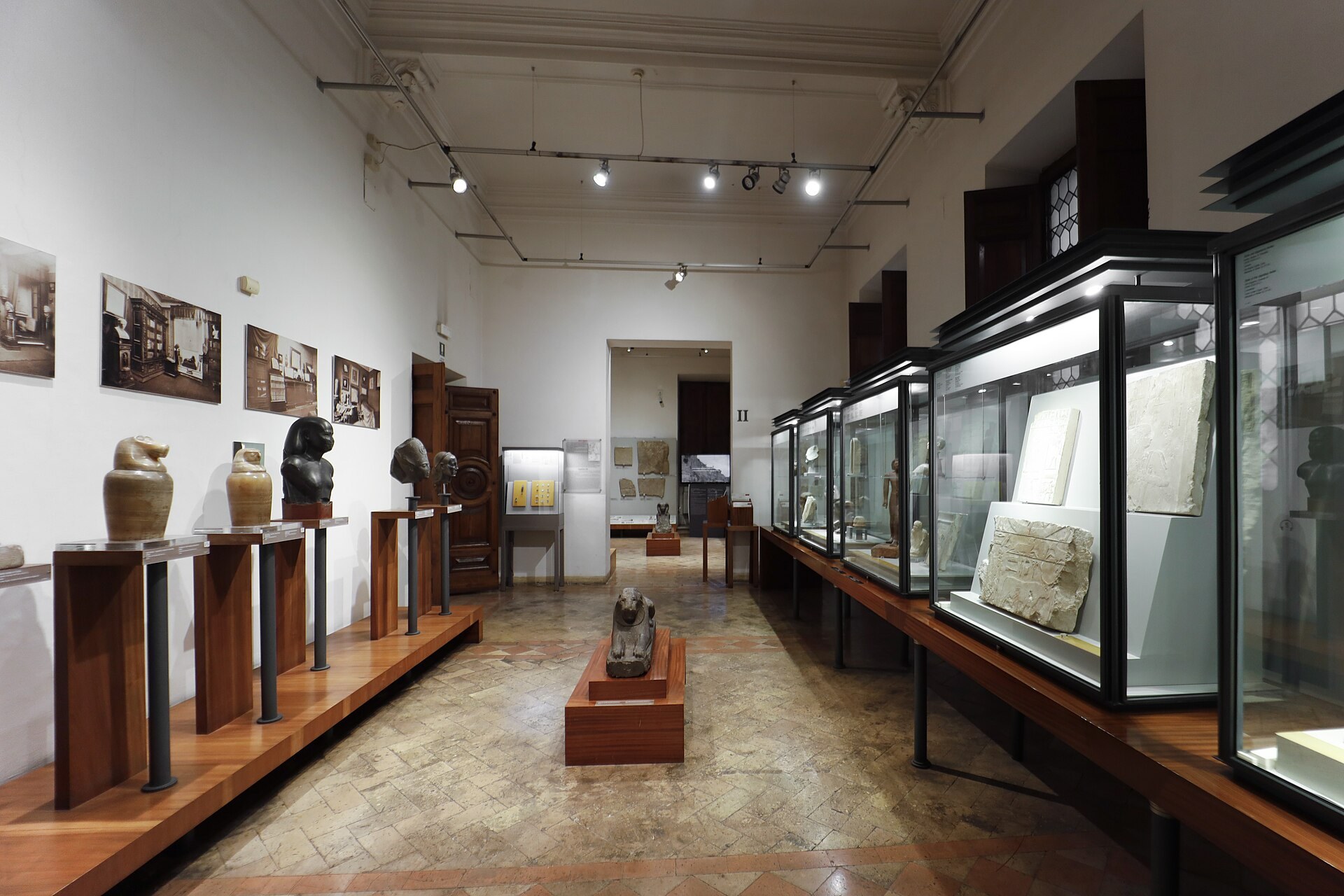 la sala del arte egipcio del museo barracco con las vitrinas junto a la pared derecha, las esculturas sobre plintos bajos y los paneles ilustrados a la izquierda