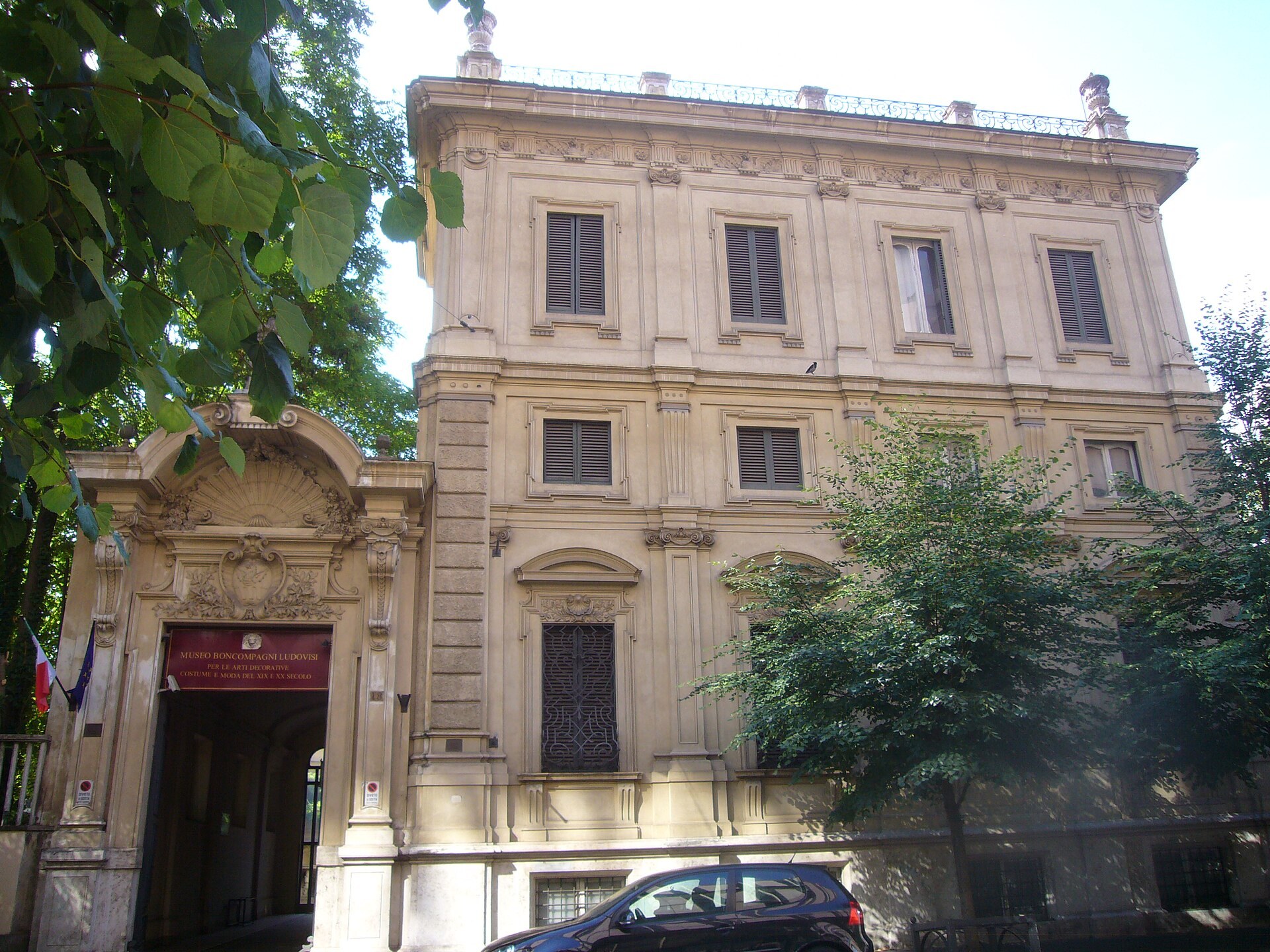 el palacete boncompagni ludovisi en via boncompagni, con el portal esculpido y las banderas en la entrada, las tres filas de ventanas y los arboles delante