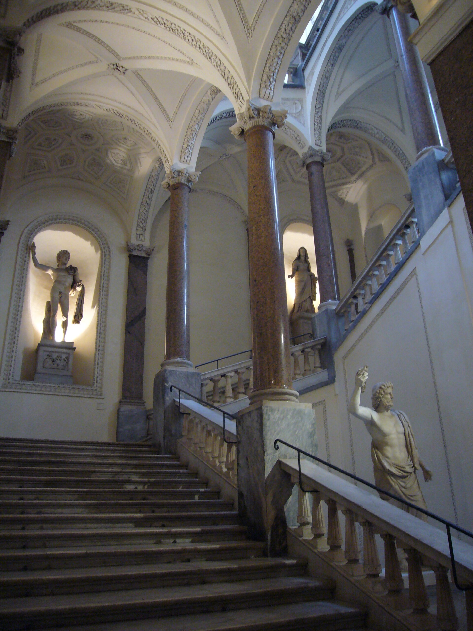 lo scalone d onore di palazzo braschi con le colonne di granito rosso, le volte a stucco e le statue antiche nelle nicchie illuminate