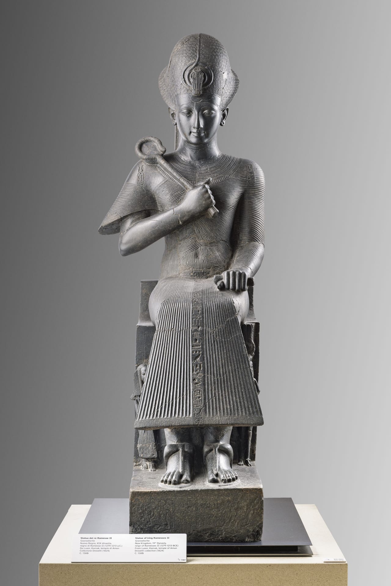 the seated statue of ramesses ii in granodiorite at the museo egizio in turin, the crown and pleated kilt carved in dark stone