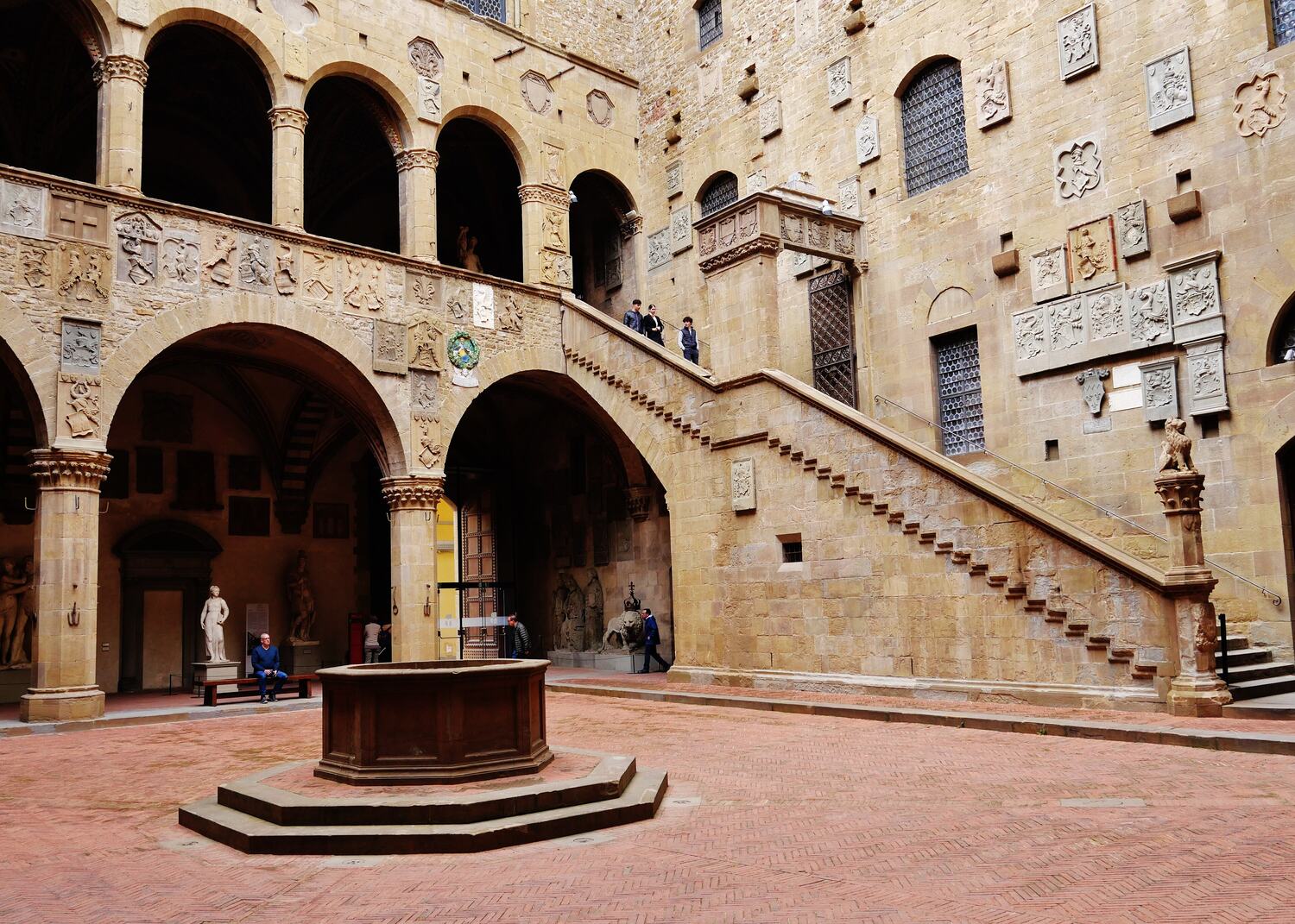 il cortile del palazzo del bargello a firenze, con la scala aperta e gli stemmi sulle pareti
