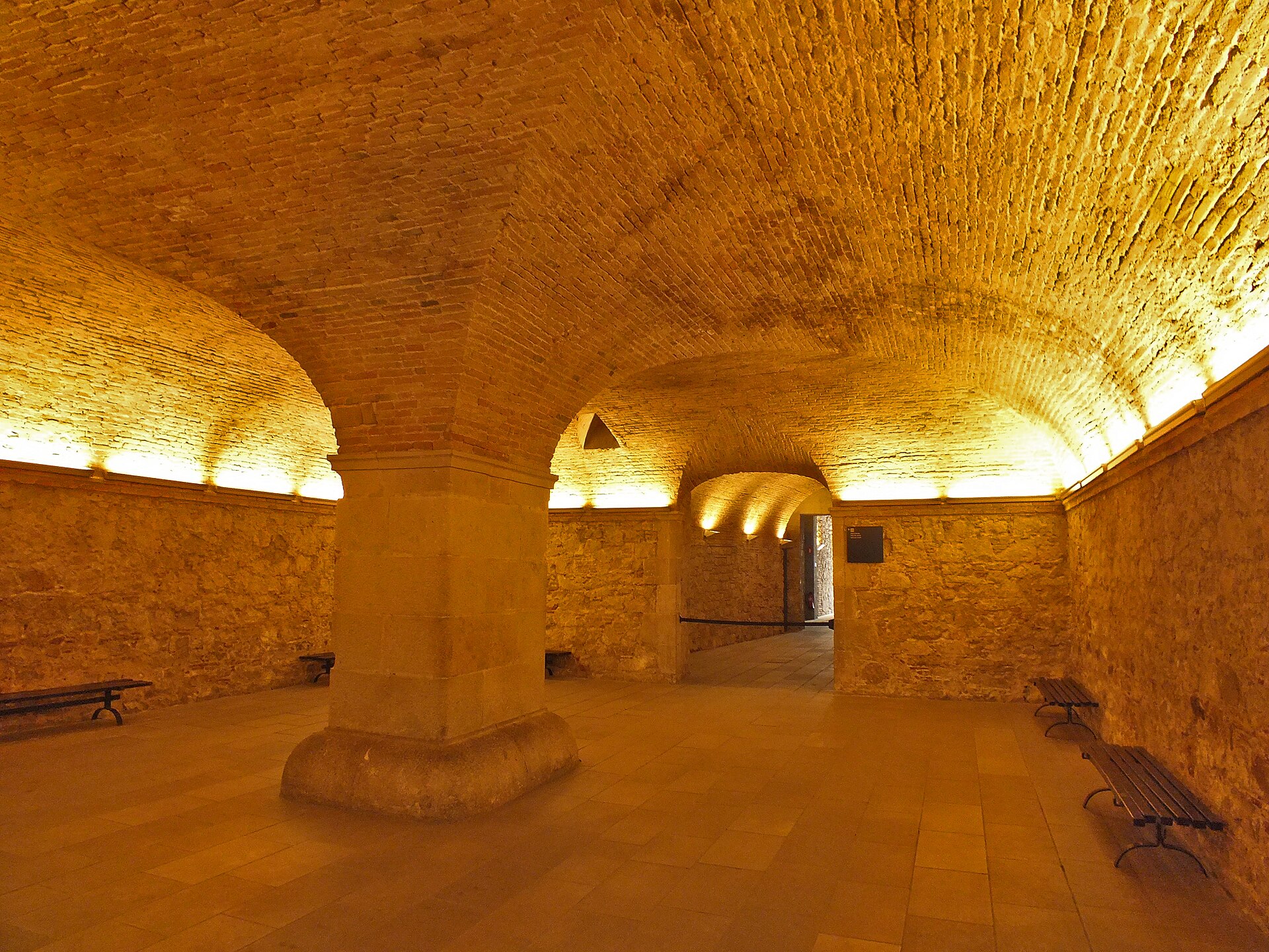 la sala al pianterreno del palau del baro de castellet, con la volta di mattoni illuminata che poggia su un grosso pilastro centrale