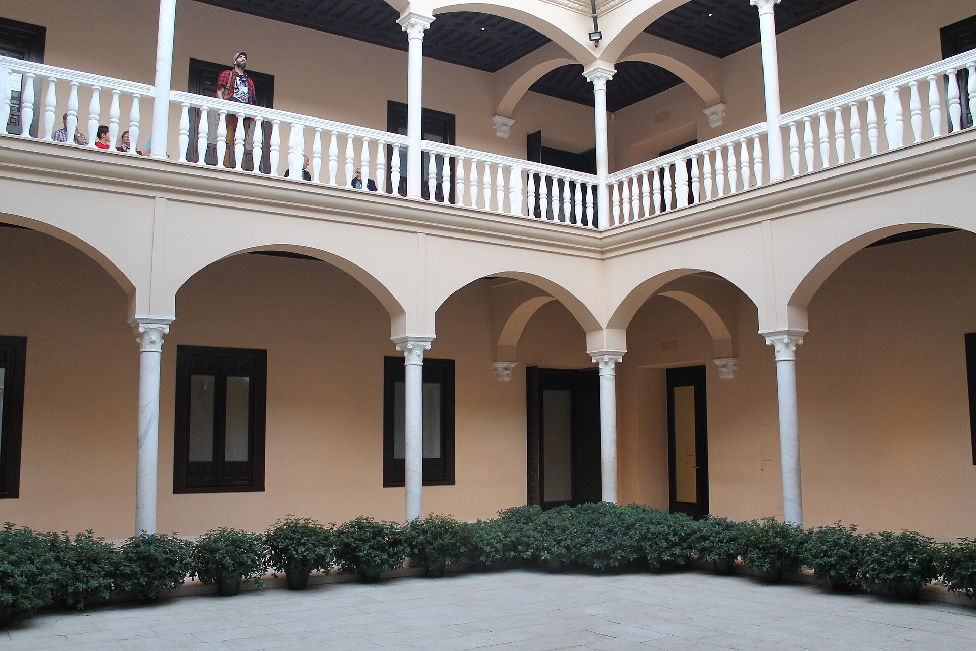 il patio del palacio de buenavista, sede del museo picasso malaga, con gli archi su colonne bianche al piano terra, la loggia con la balaustra al piano di sopra e le piante in vaso lungo il perimetro