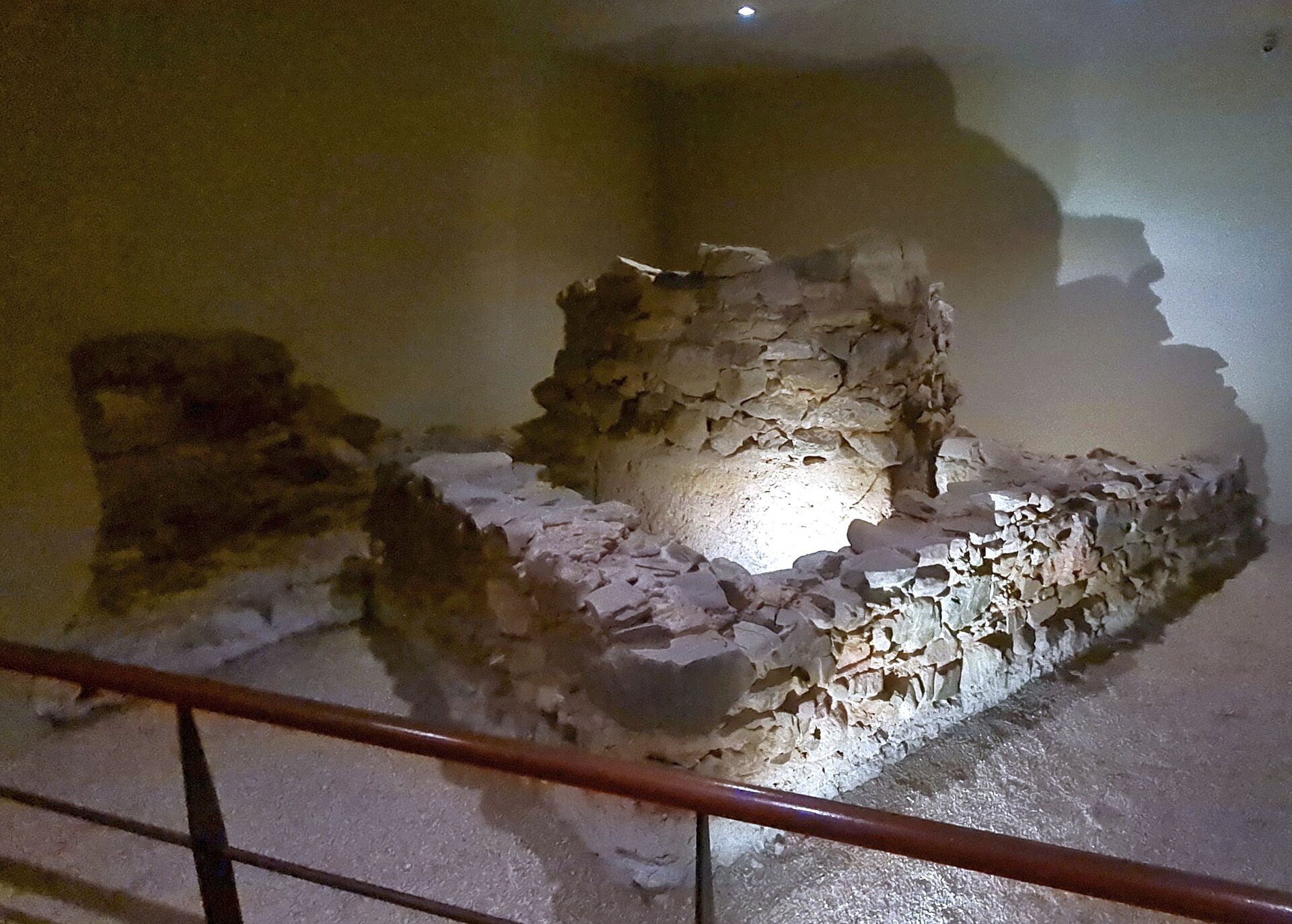 muri antichi di pietra nel sottosuolo del palacio de buenavista, illuminati da un faro dietro una ringhiera