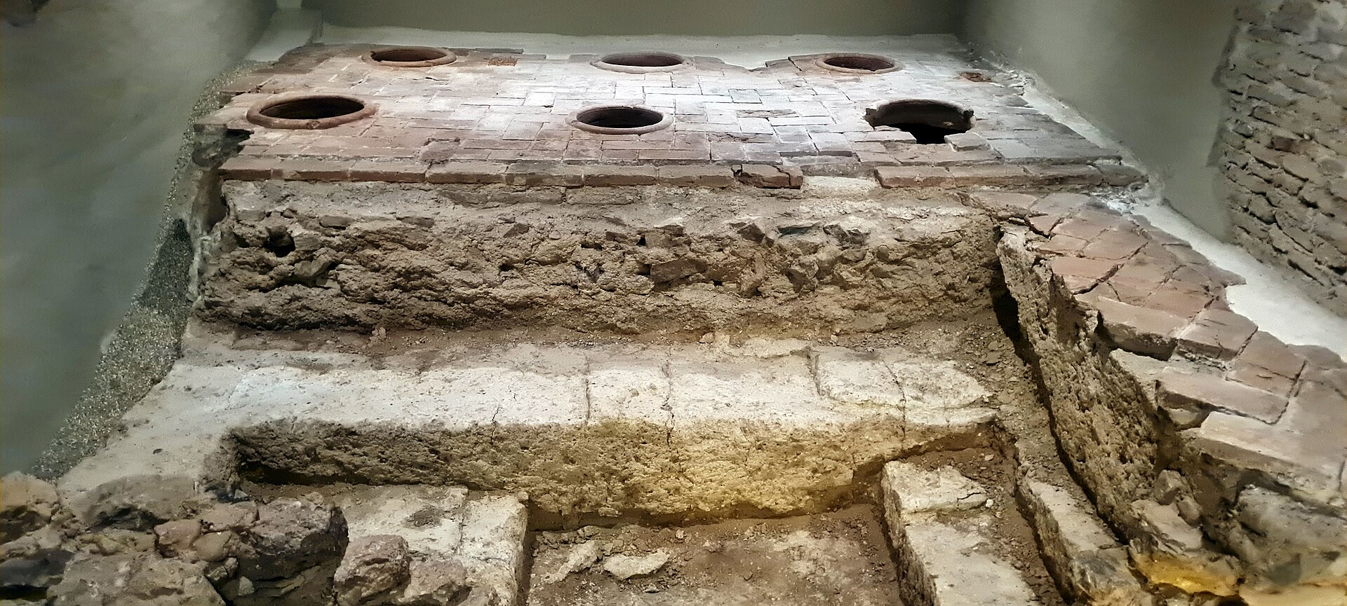 un pavimento antico di mattoni nel sottosuolo del palacio de buenavista, con le bocche rotonde di sei giare incassate