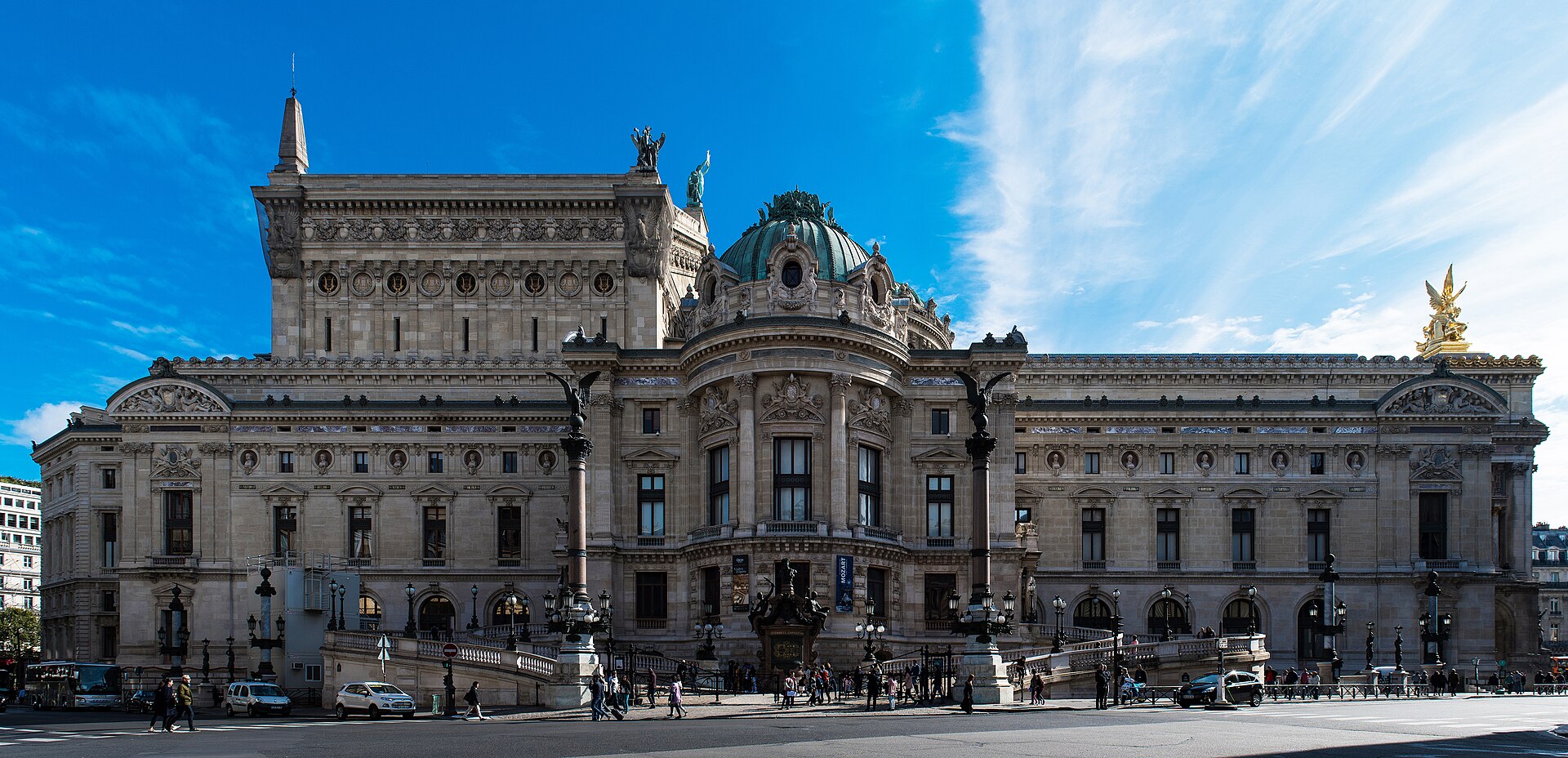 la facciata ovest del palais garnier con la cupola verde, la statua dorata alata sul tetto contro un cielo azzurro terso e la facciata in pietra chiara