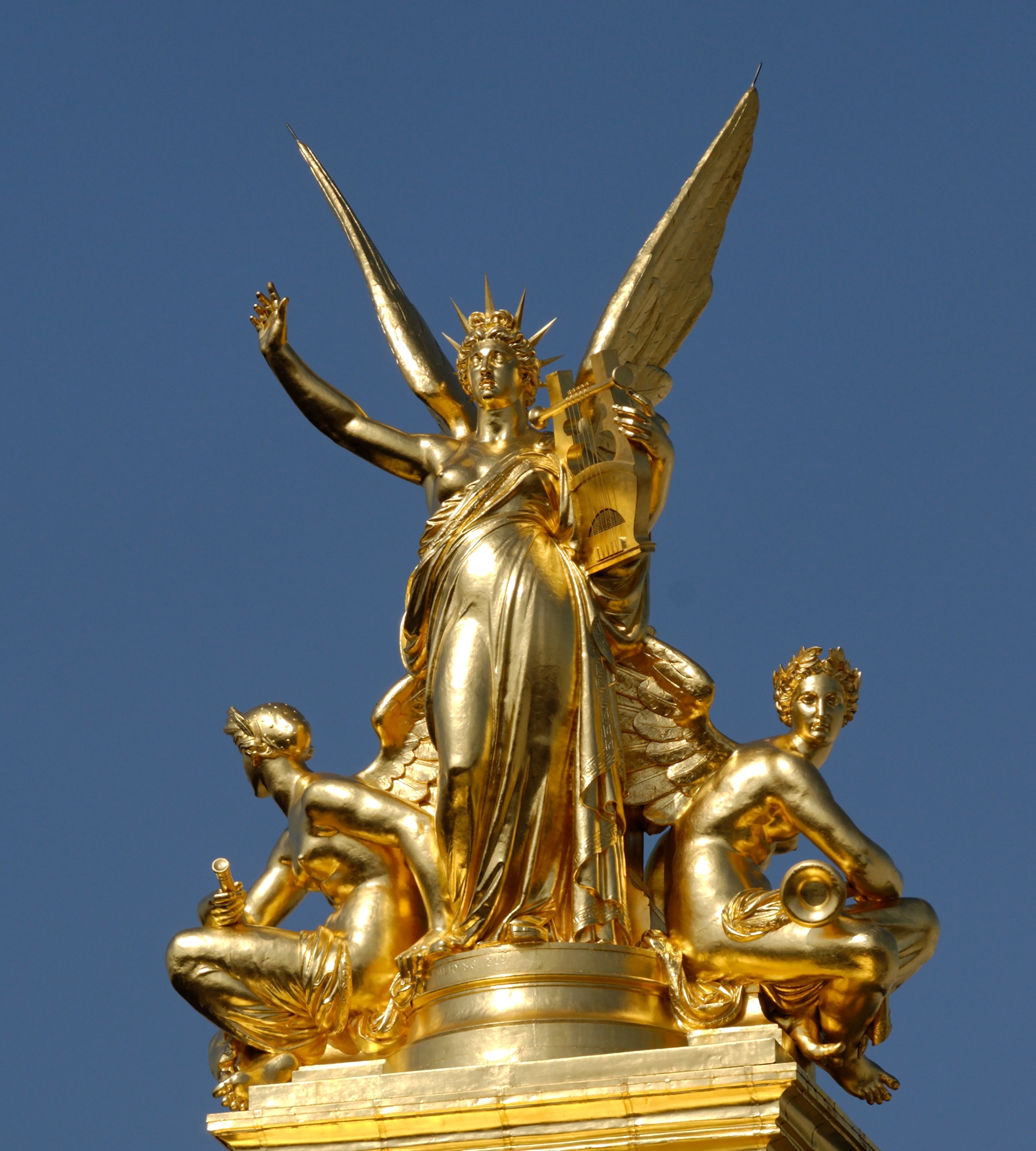 il gruppo scultoreo dorato dell armonia di charles gumery sul tetto del palais garnier, una figura femminile alata con le braccia aperte e due geni accovacciati ai lati, contro un cielo azzurro