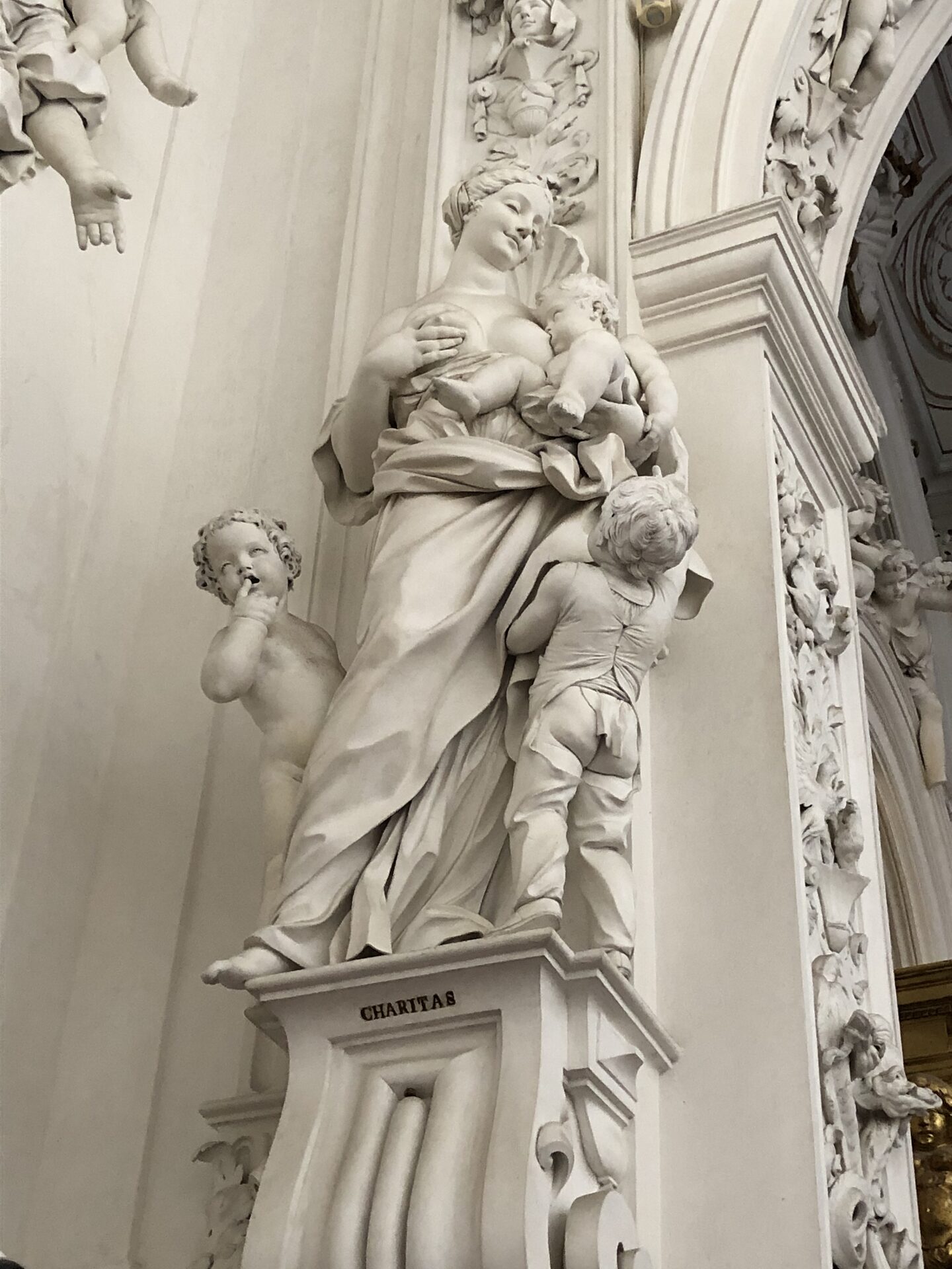 a white stucco statue of charity by serpotta with children around her