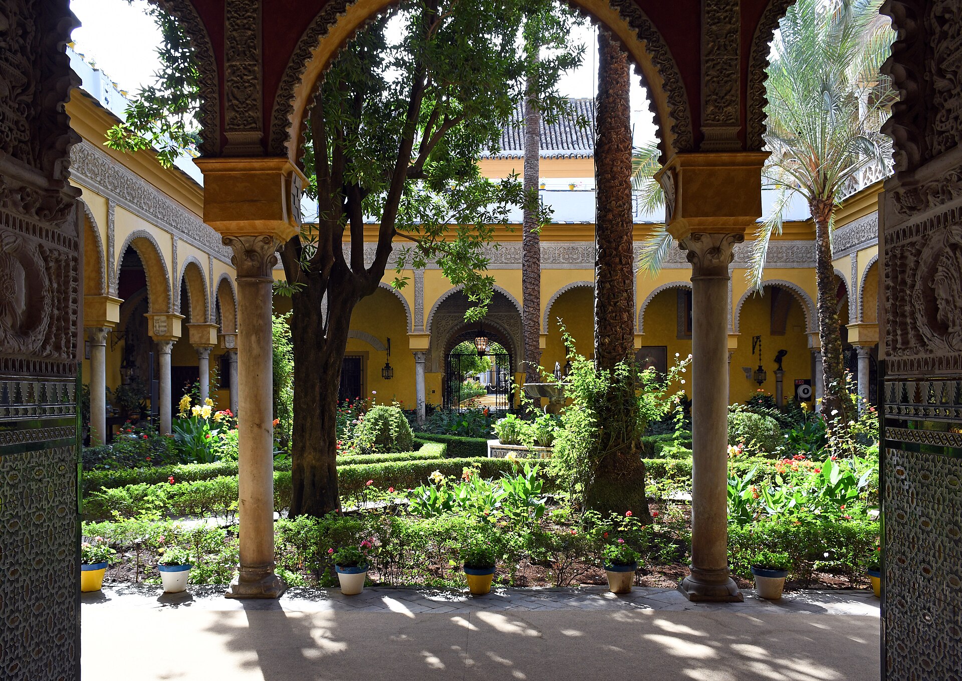gli archi del patio principale del palacio de las duenas visti dalla galleria, con le colonne di marmo, gli stucchi e il giardino del patio