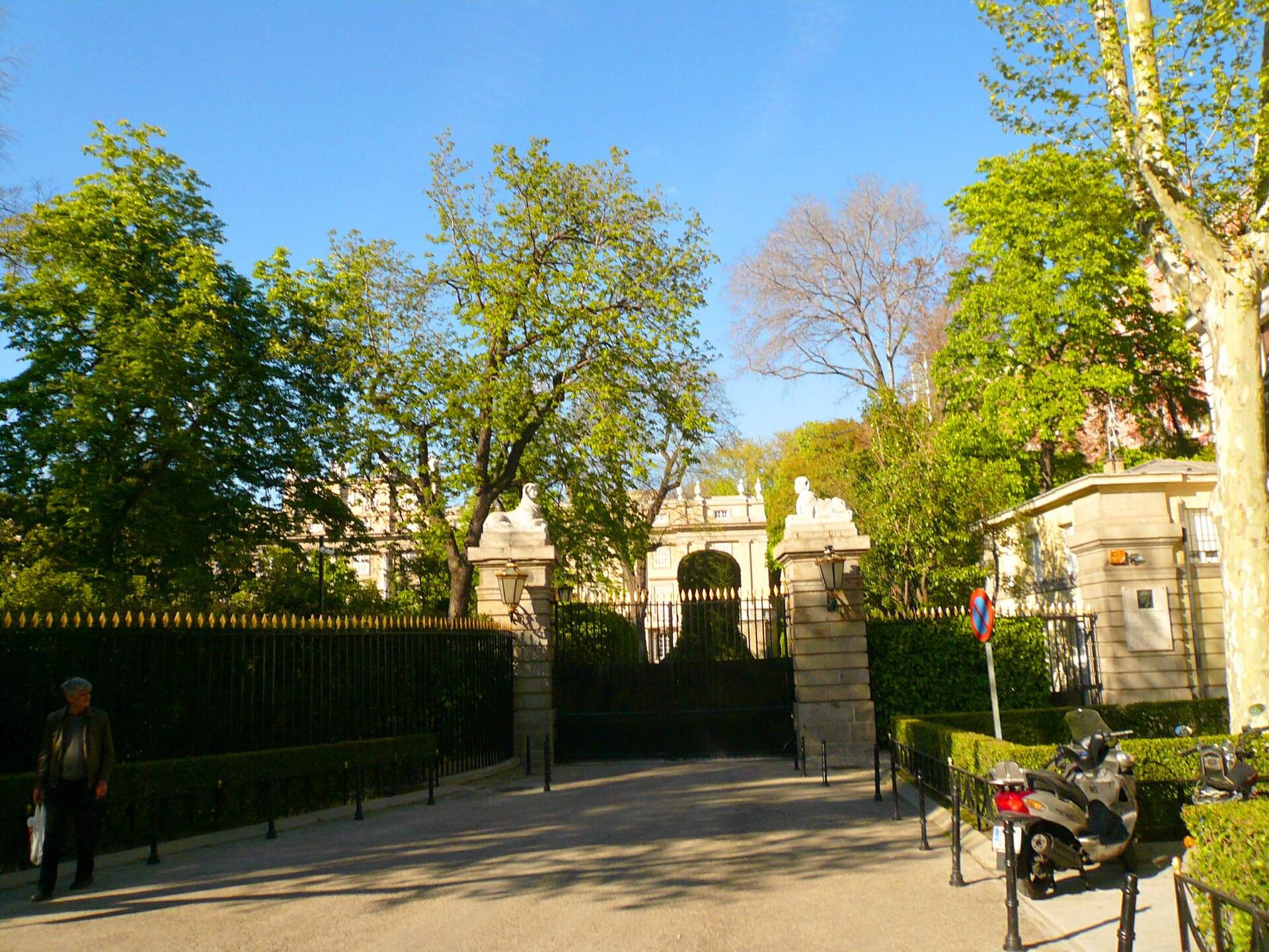 il cancello d’ingresso del palacio de liria su calle de la princesa, fra due pilastri di pietra con due sfingi, con la cancellata, gli alberi del giardino e la facciata del palazzo sullo sfondo